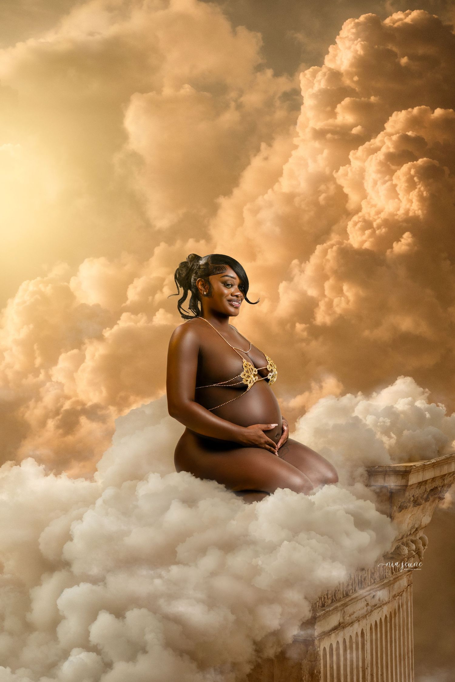 Stunning maternity photo featuring a silhouette against golden clouds and classical architecture in a dreamy setting.