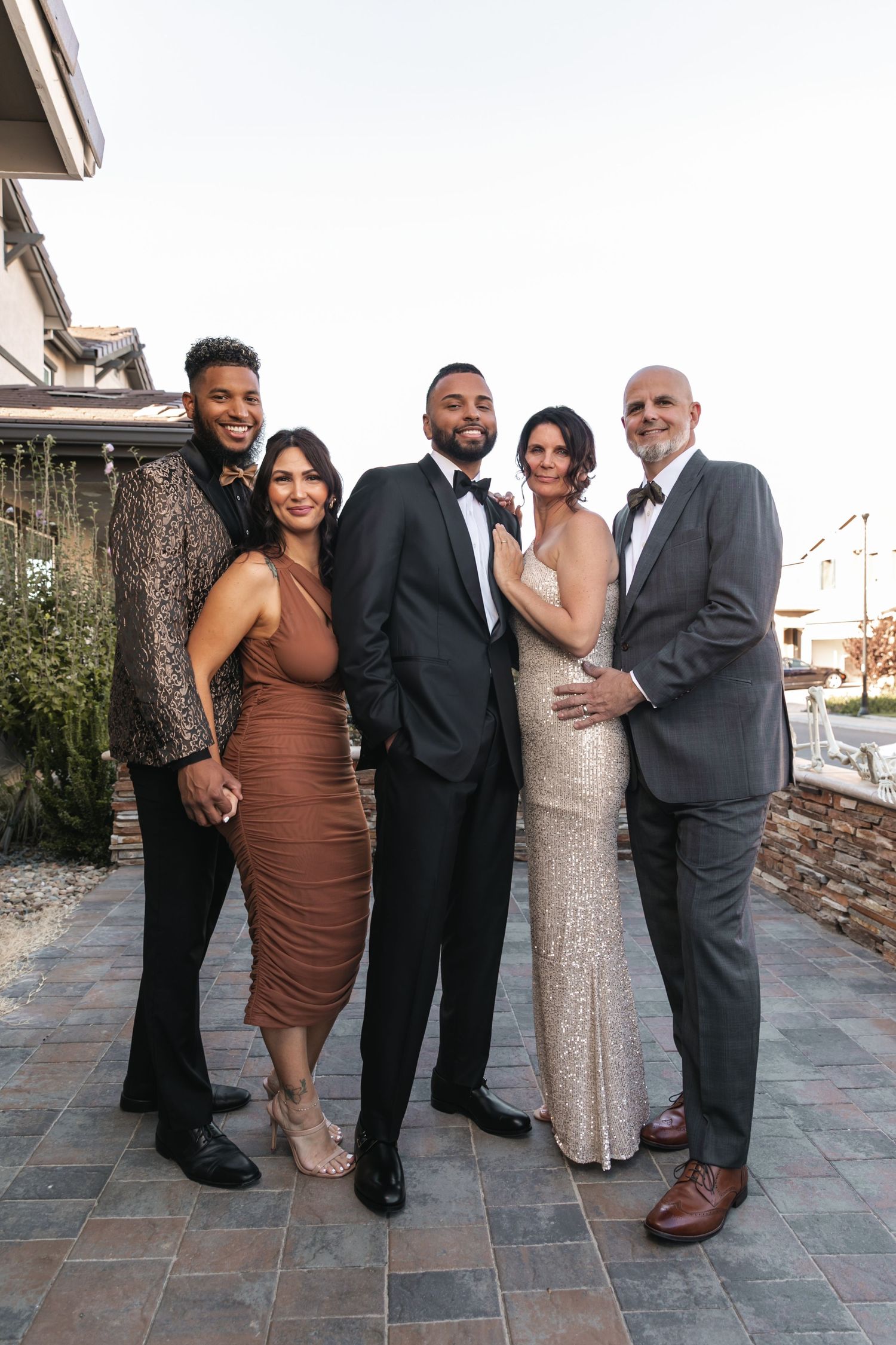 Two couples stand together on a decorative outdoor patio for a formal group photo.