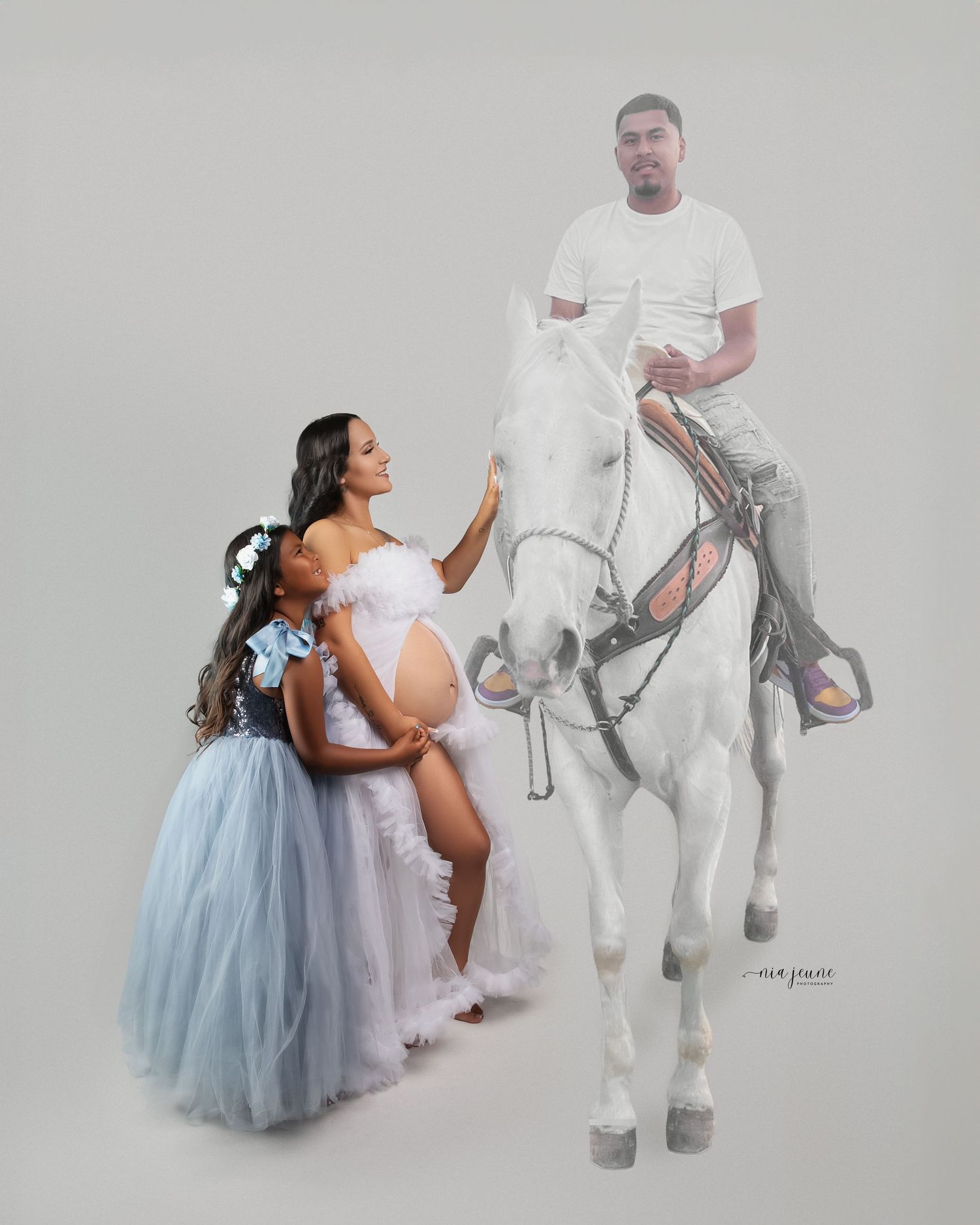 Whimsical maternity session with tulle dresses and unicorn props against a grey backdrop.