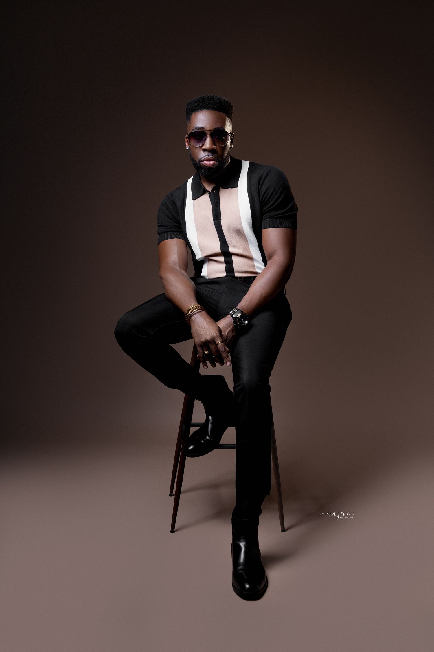 Modern portrait session against brown backdrop featuring black and white fashion ensemble.