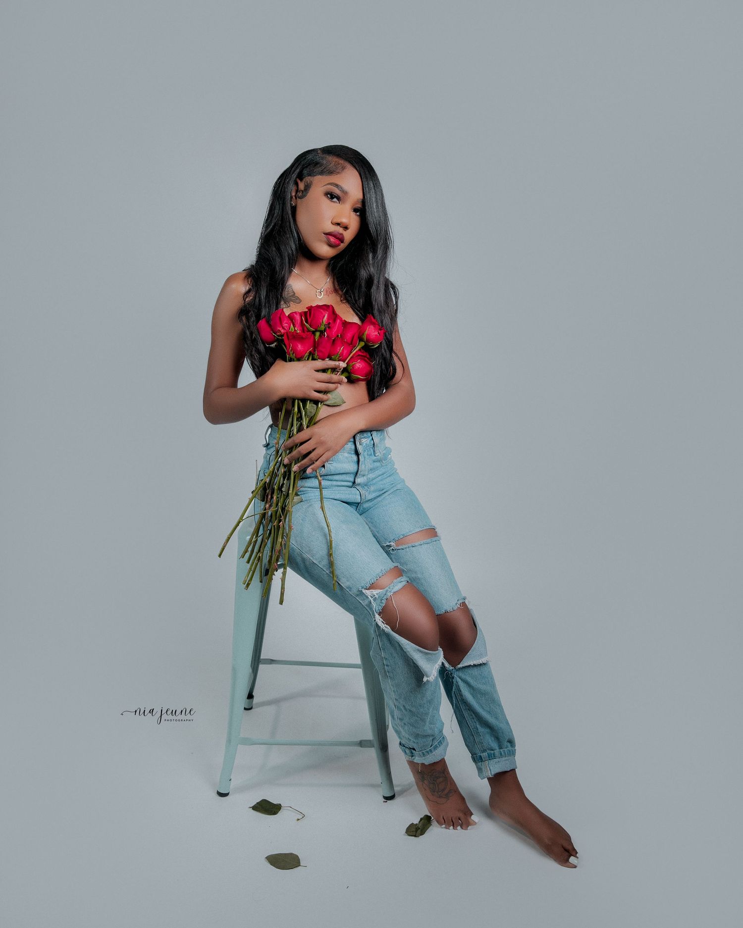 Fashion portraits featuring distressed denim and red roses against a neutral grey background.