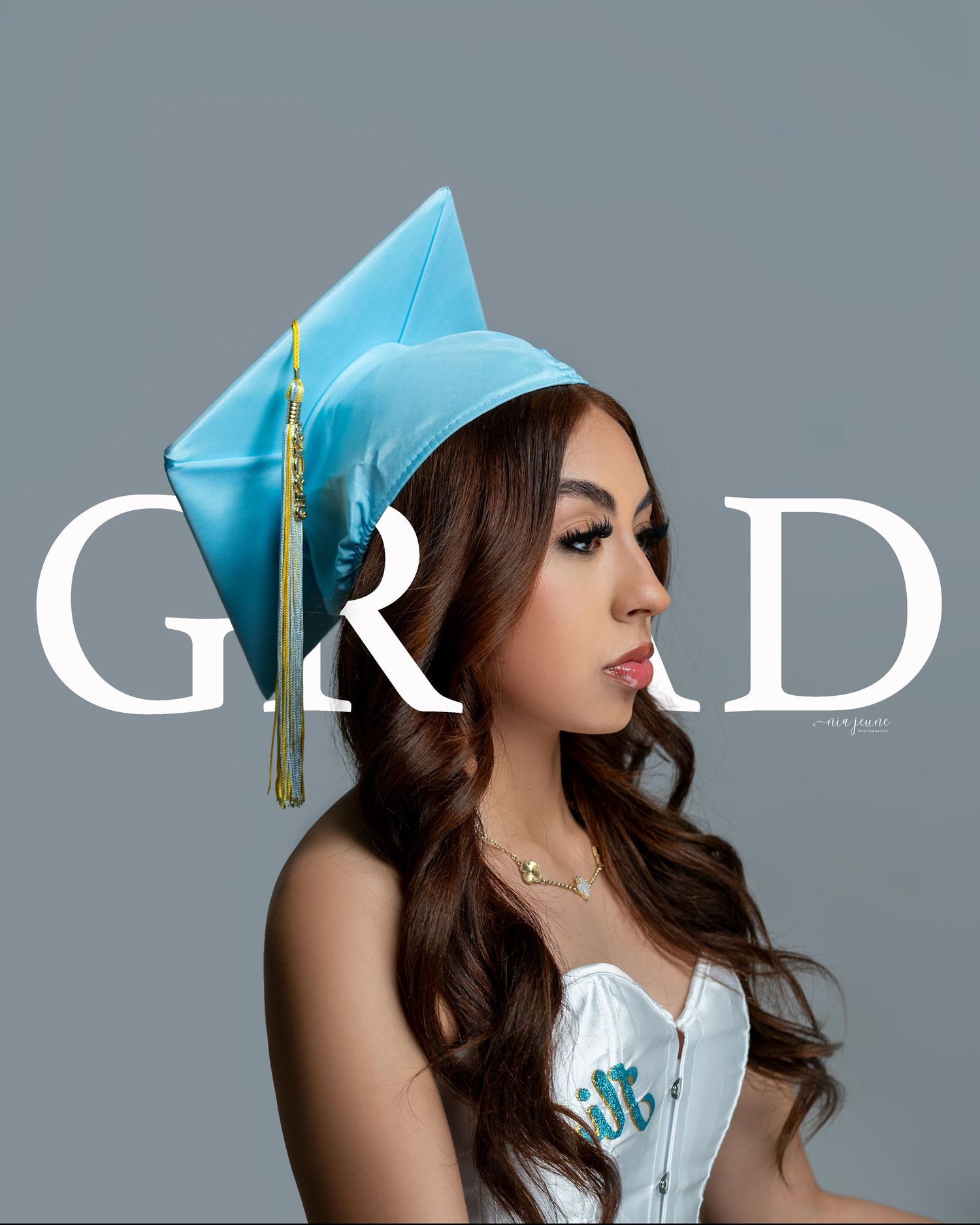 Graduate in light blue cap with tassel against grey background with GRAD text overlay.