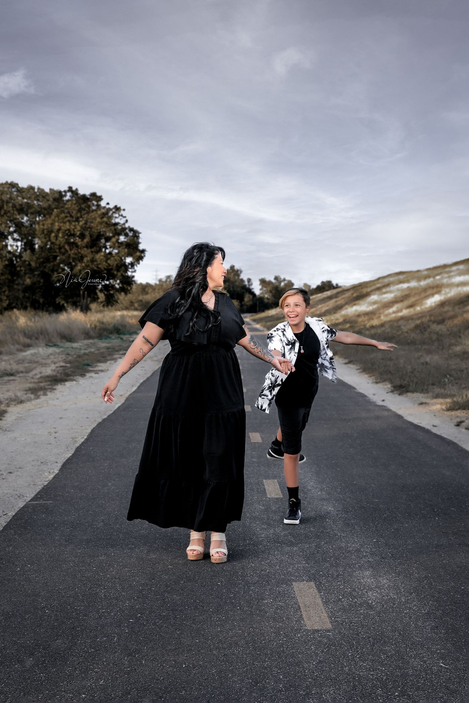 Two people dancing together on an asphalt road surrounded by natural scenery.