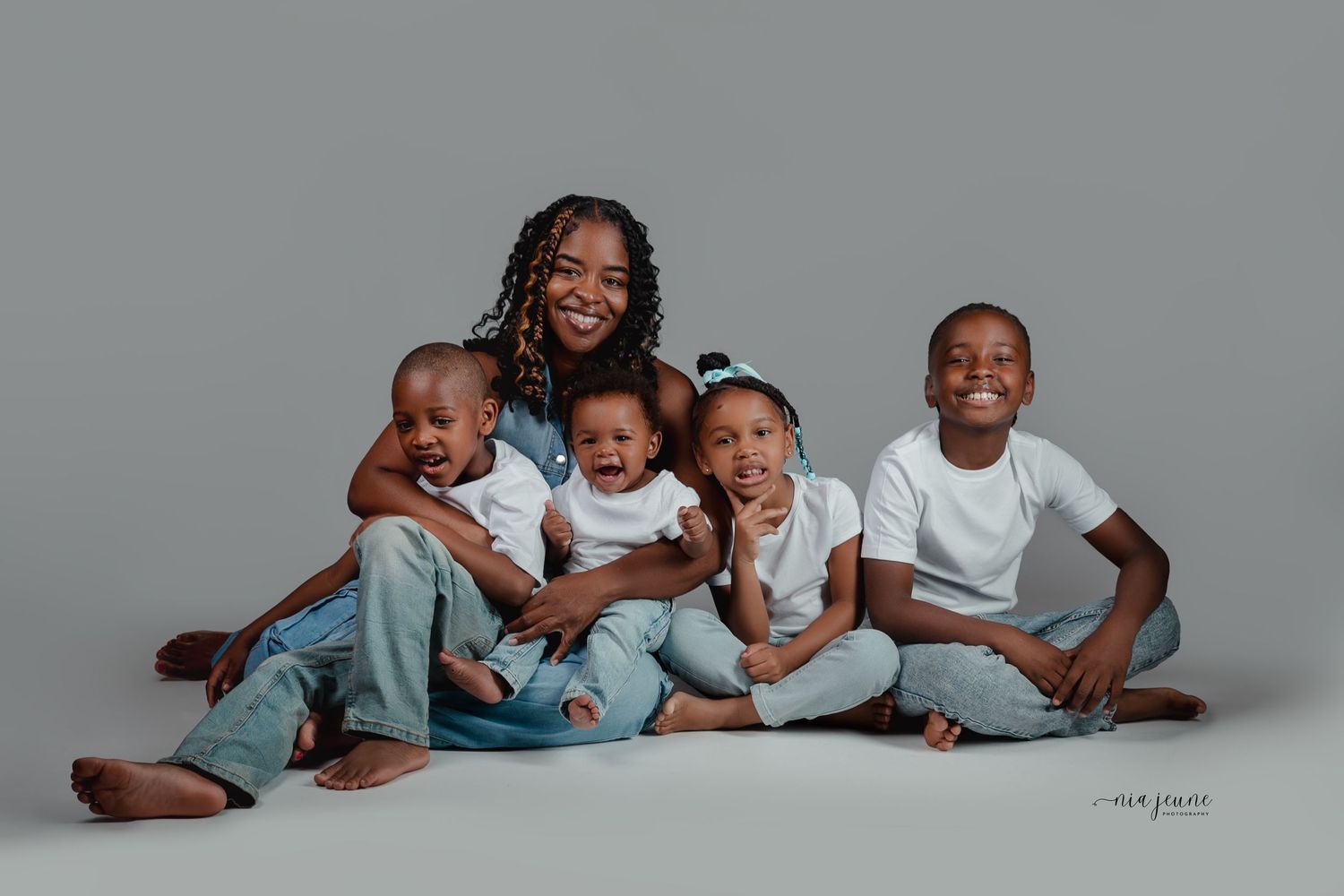 A playful group photo set showing siblings laying down and posing together in coordinated blue and white outfits.