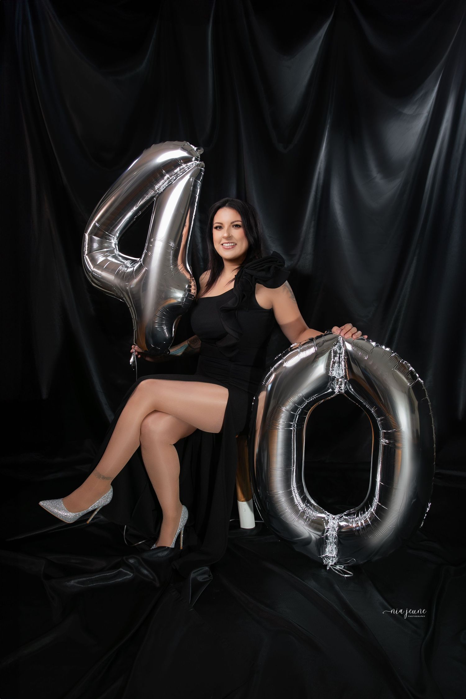 A glamorous 40th birthday photoshoot featuring large silver number balloons against a black backdrop.
