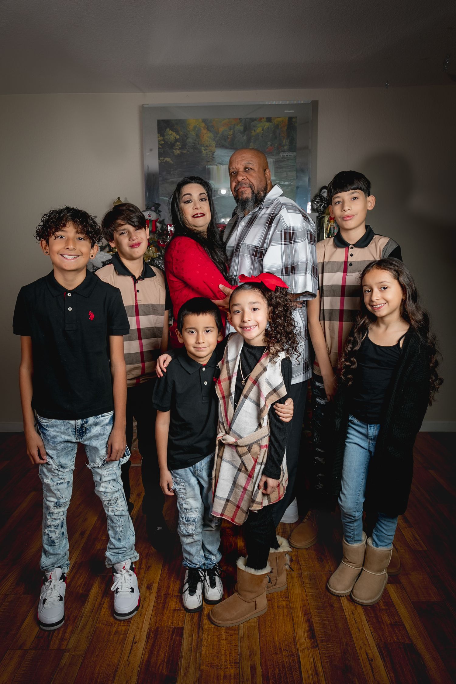 Family portrait of adults and children in coordinated plaid and casual outfits.