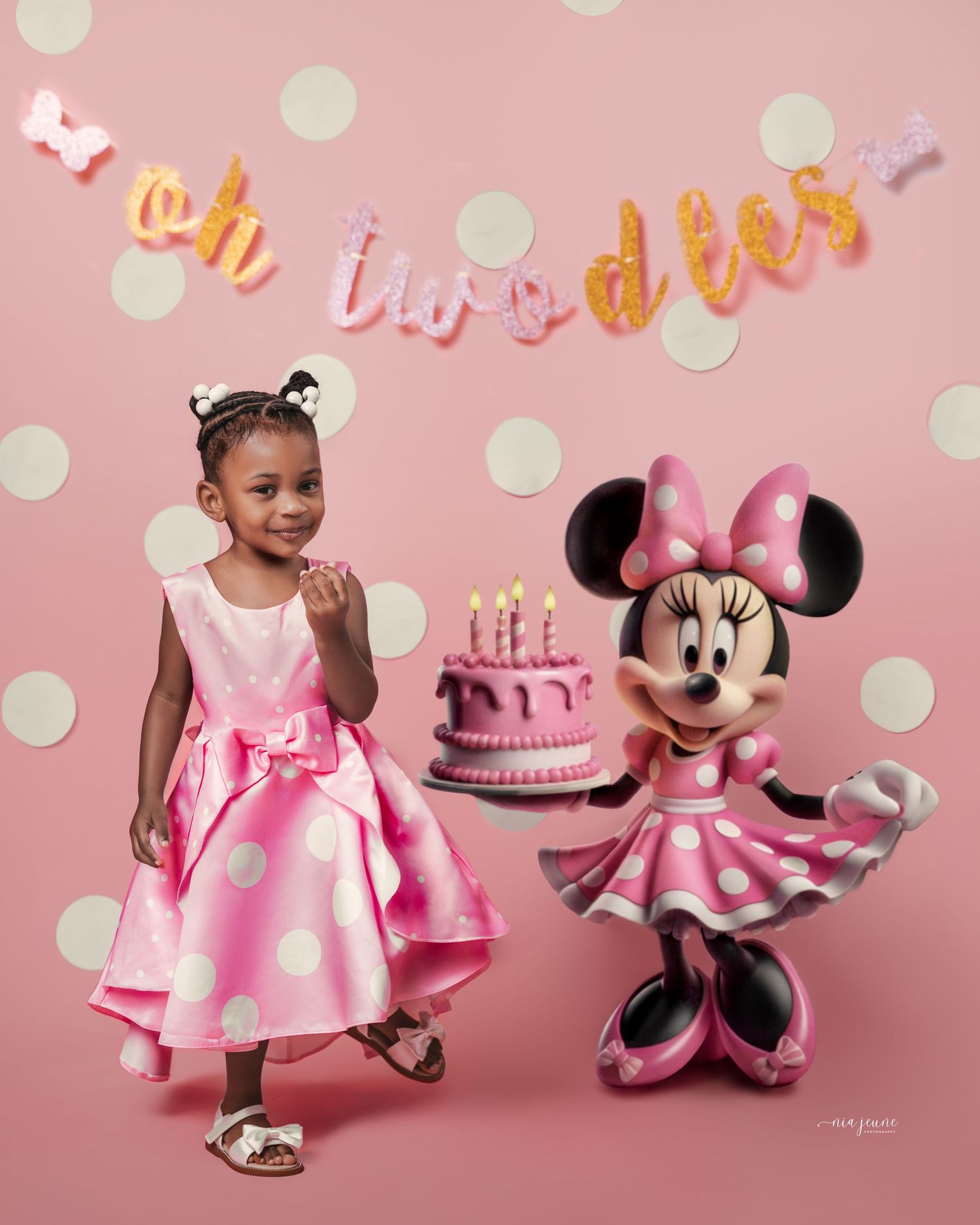 Pink polka dot birthday celebration setup with Minnie Mouse balloon and birthday cake against a pink backdrop.
