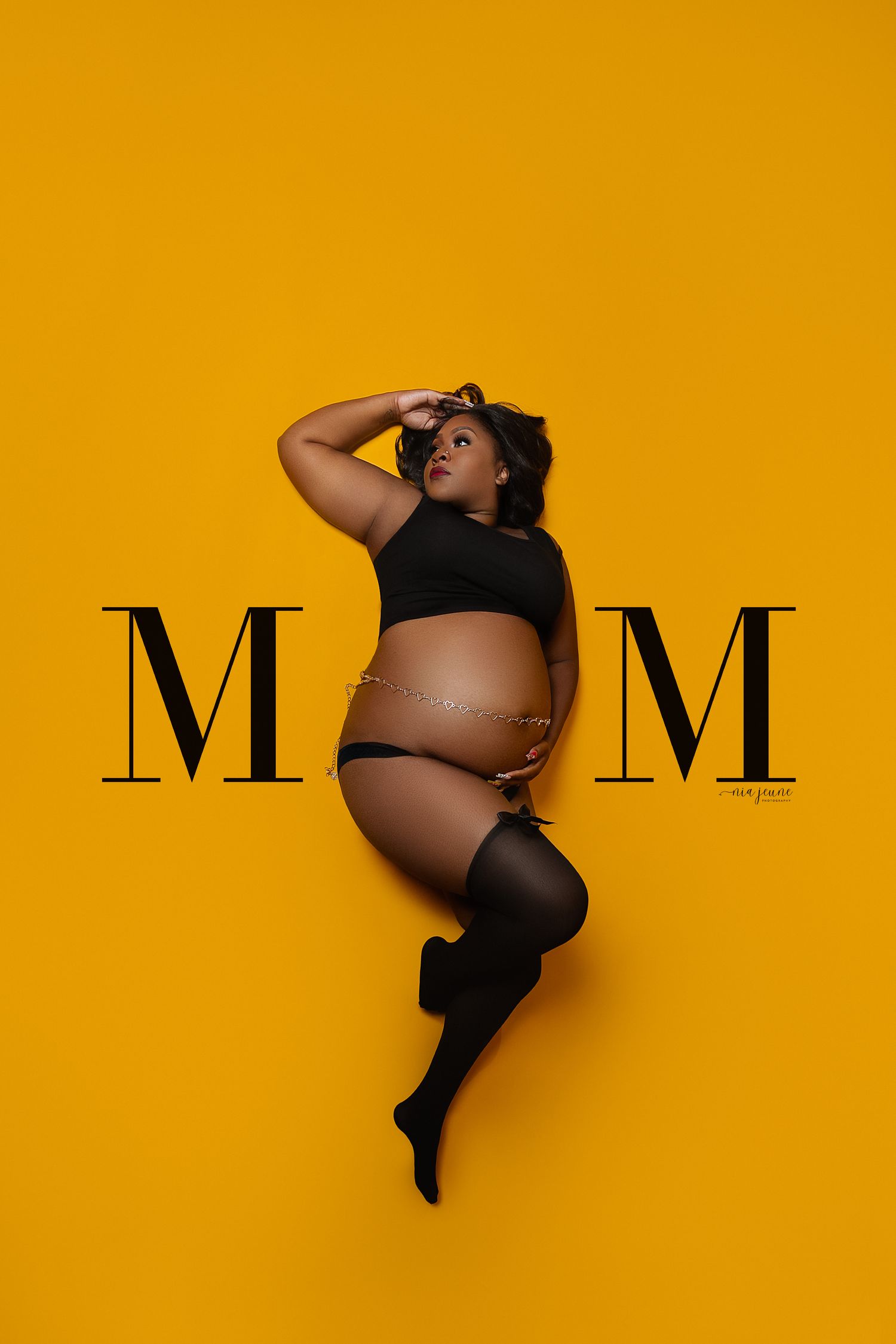 A maternity photoshoot against a vibrant yellow background showcases the beauty of pregnancy in a black outfit.