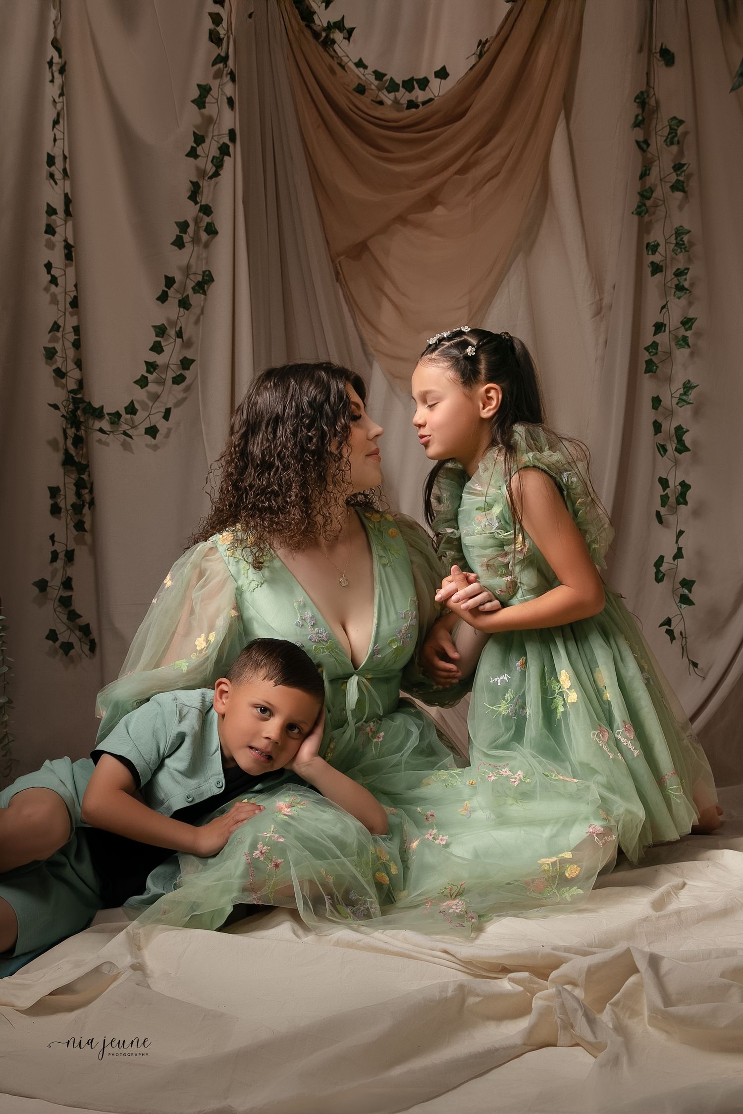 A artistic family portrait featuring coordinated mint green outfits against a draped fabric backdrop.