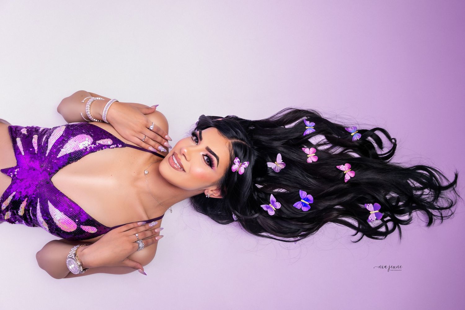 Creative portrait with purple spider web design and flowing black hair against gradient background.