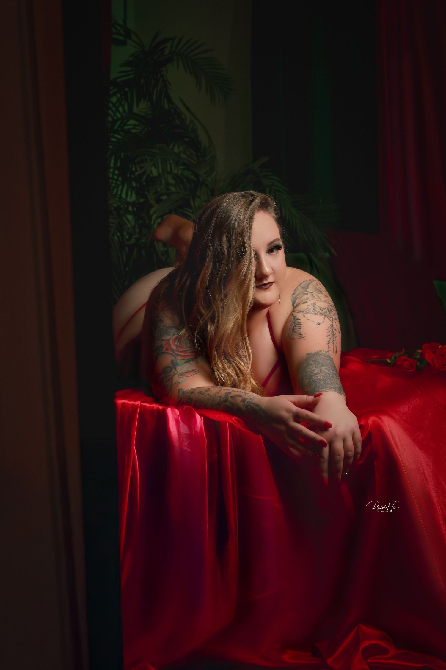 Artistic boudoir photoshoot with red silk fabric in moody lighting.