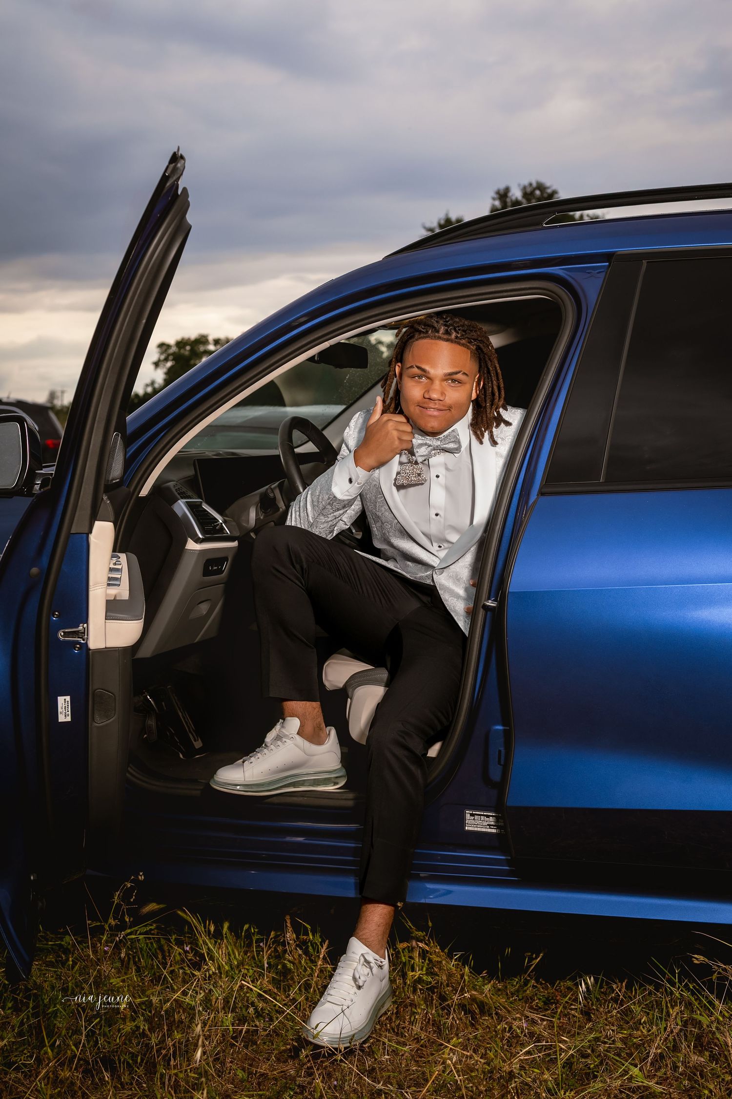 Athletic casual portrait of someone sitting in a blue car wearing Nike sneakers and athleisure wear.