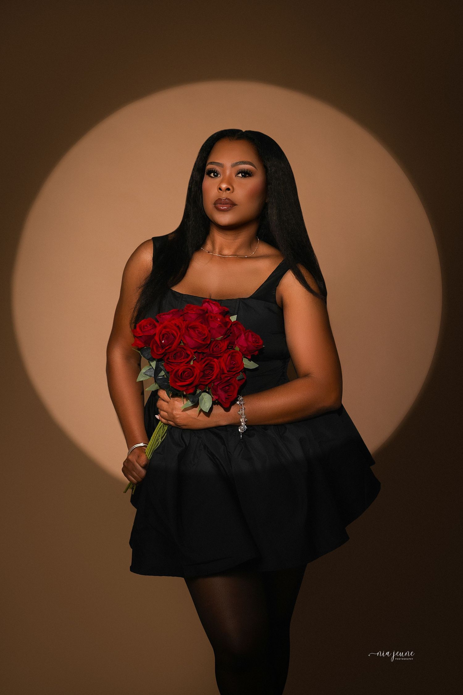 Artistic portrait series in black dress holding red roses against moody brown backdrop with dramatic lighting and shadows.