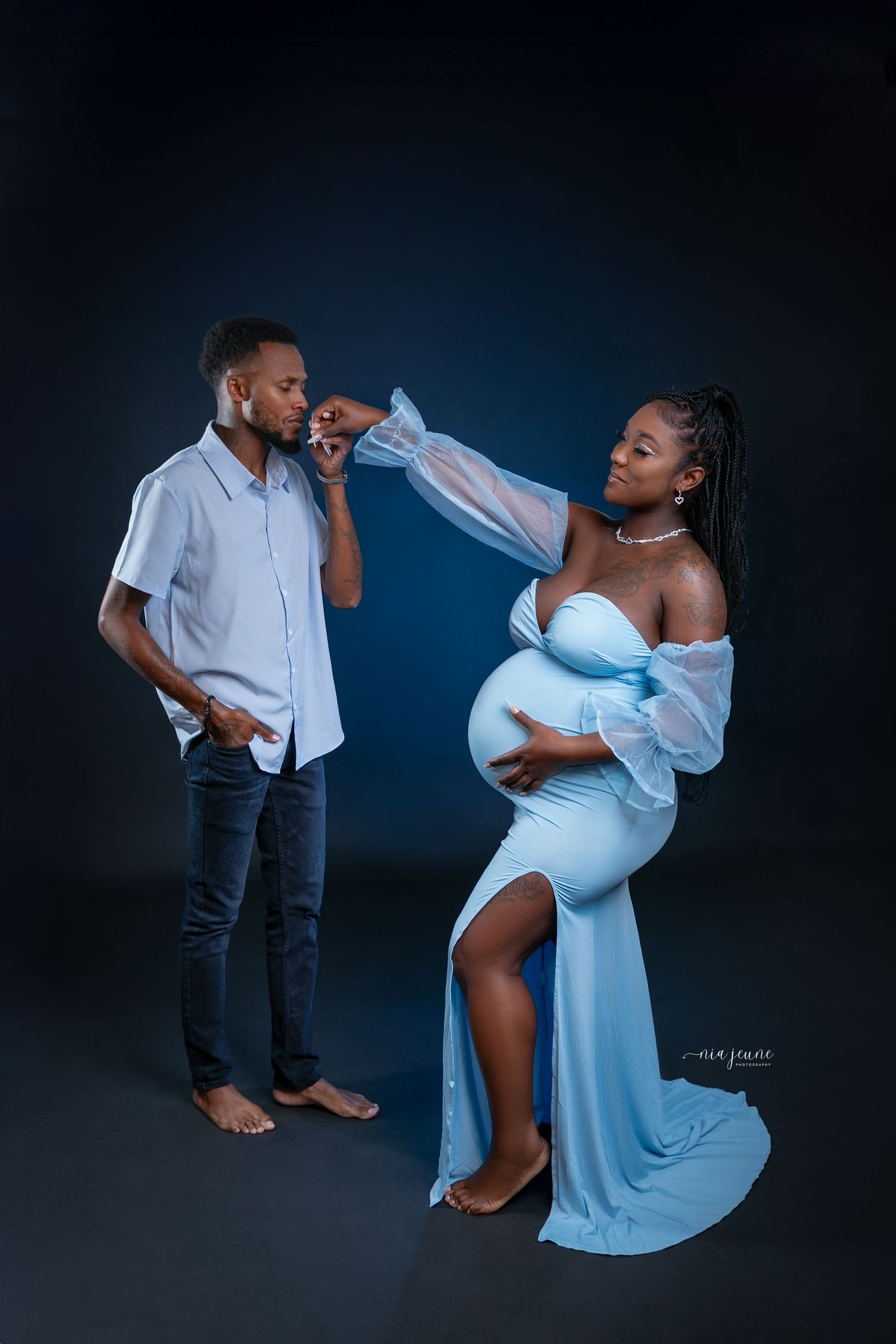 A dramatic maternity photoshoot series against a dark blue backdrop features flowing fabric and intimate poses.