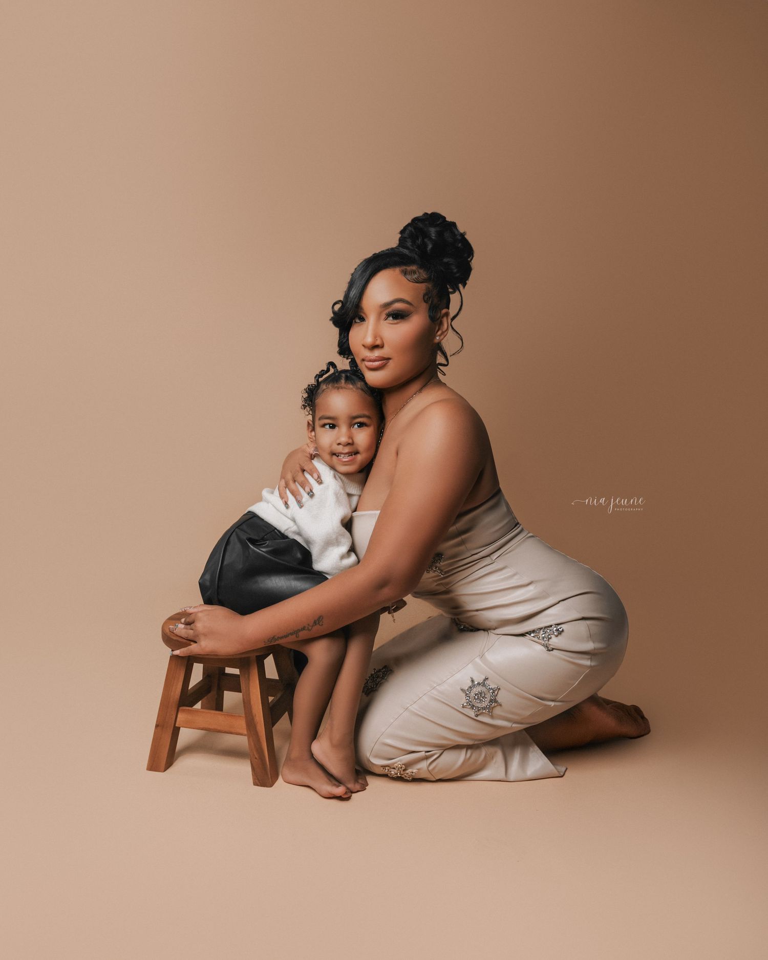 Studio portraits of parent and child in neutral tones with minimal wooden props.