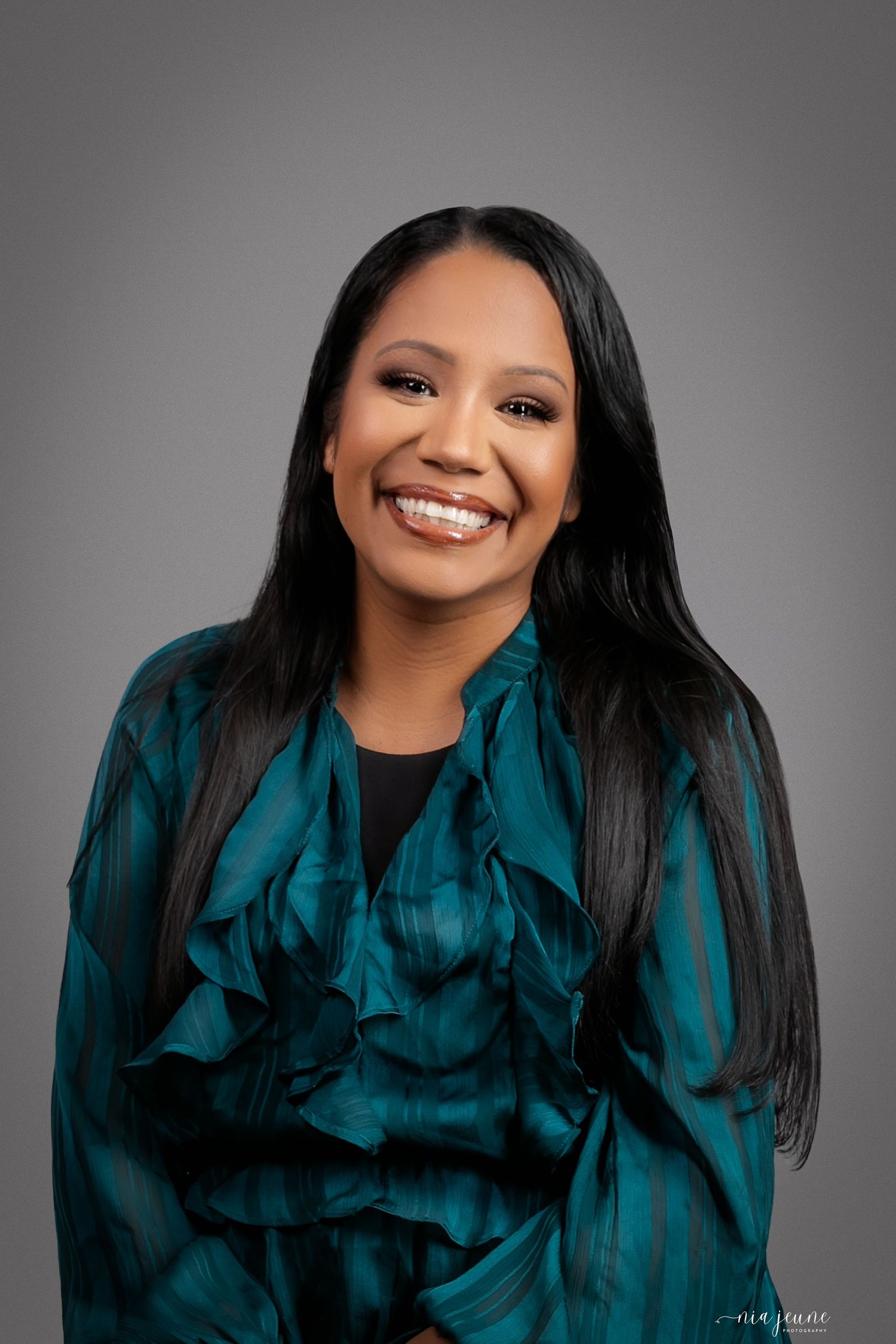 Professional studio portraits in teal outfit against grey background showcasing warm smiles and elegant poses.