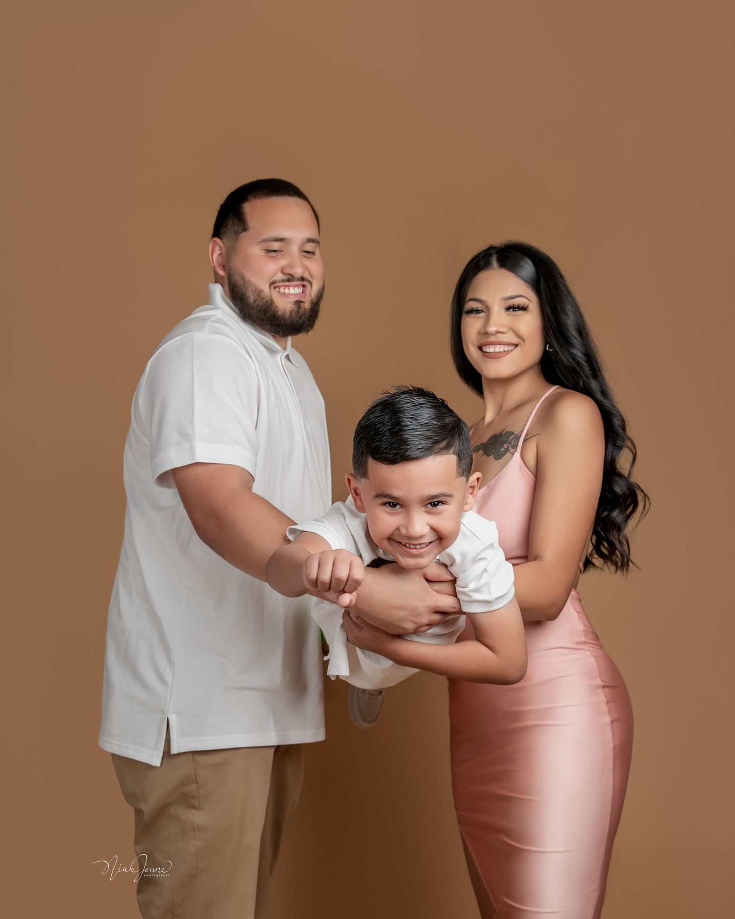 A playful studio photoshoot with a brown backdrop showing tender family moments.