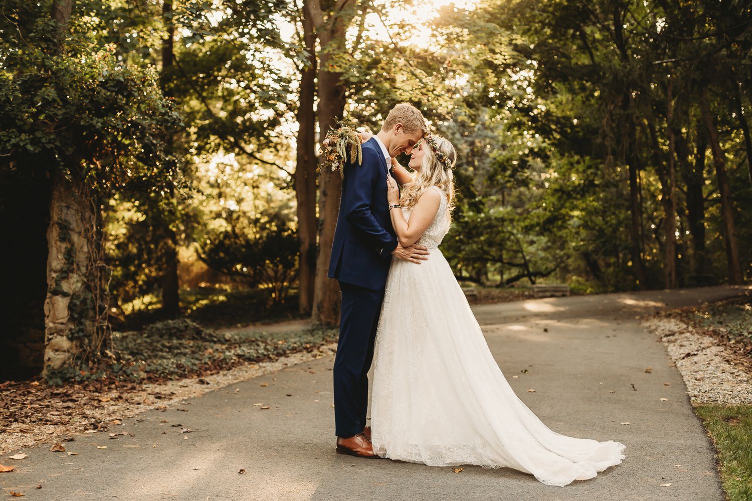 A wedding couple embraces on a tree-lined path during golden hour. Pittsburgh wedding Photographer
