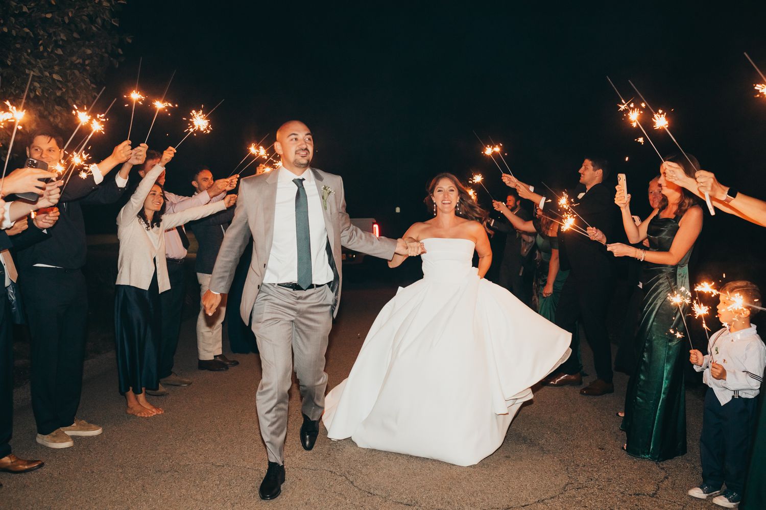 Wedding exit with couple walking through sparkler tunnel held by guests at night. Pittsburgh wedding Photographer
