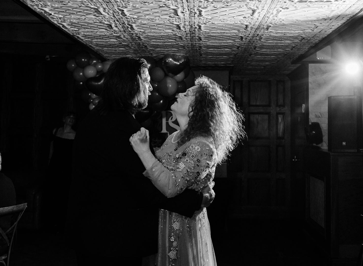 A couple dances intimately in a dark room with ornate tin ceiling and dramatic lighting. Pittsburgh wedding Photographer