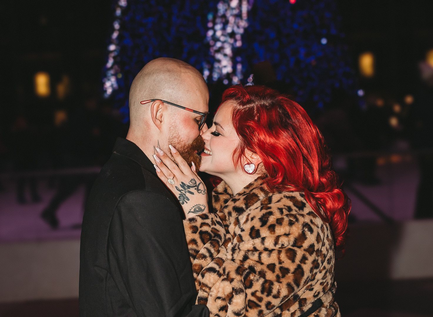 Couple sharing an intimate moment in the evening with red lighting and a leopard print coat.