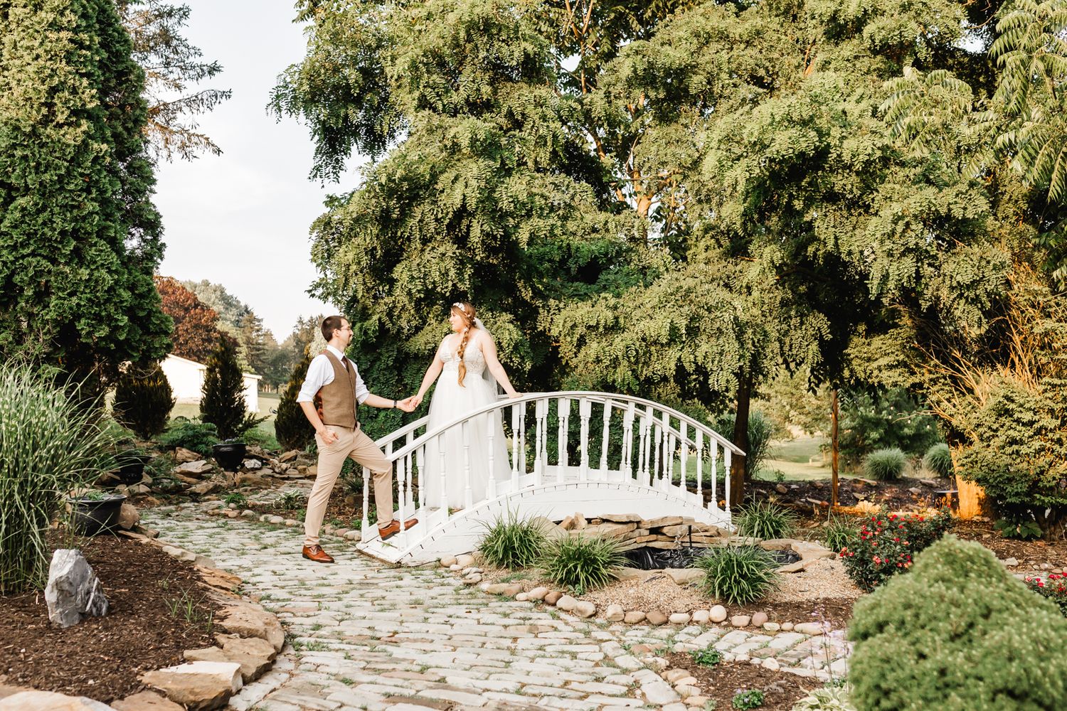 Wedding couple standing on a white bridge in a lush garden setting. Pittsburgh wedding Photographer