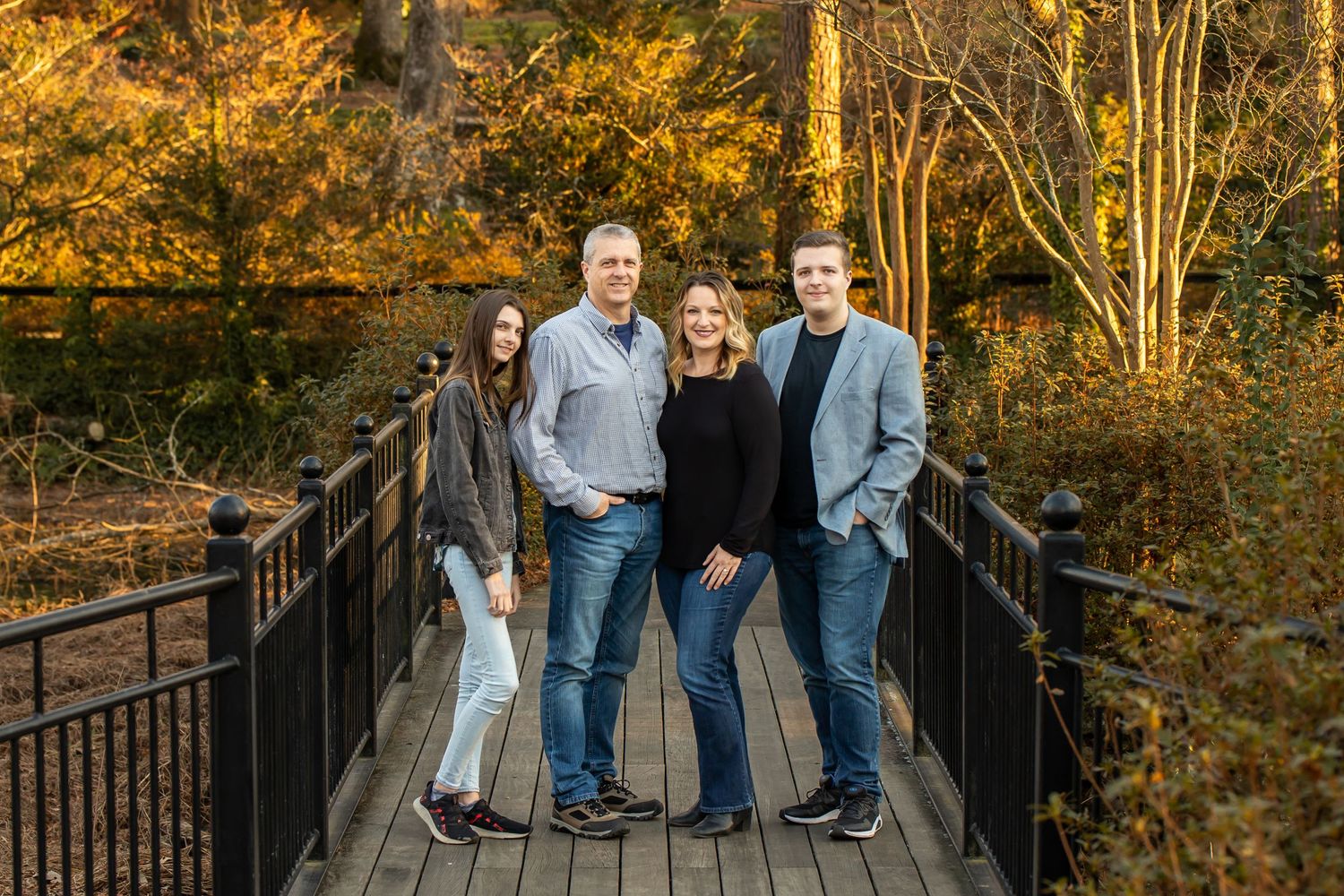 Group poses on wooden bridge surrounded by vibrant autumn foliage in golden afternoon light.