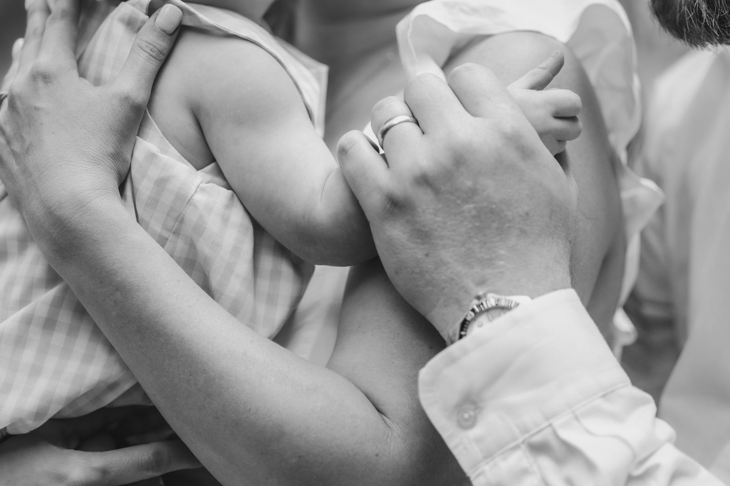 Black and white close-up of hands embracing, showing intimate connection and gentle touch.