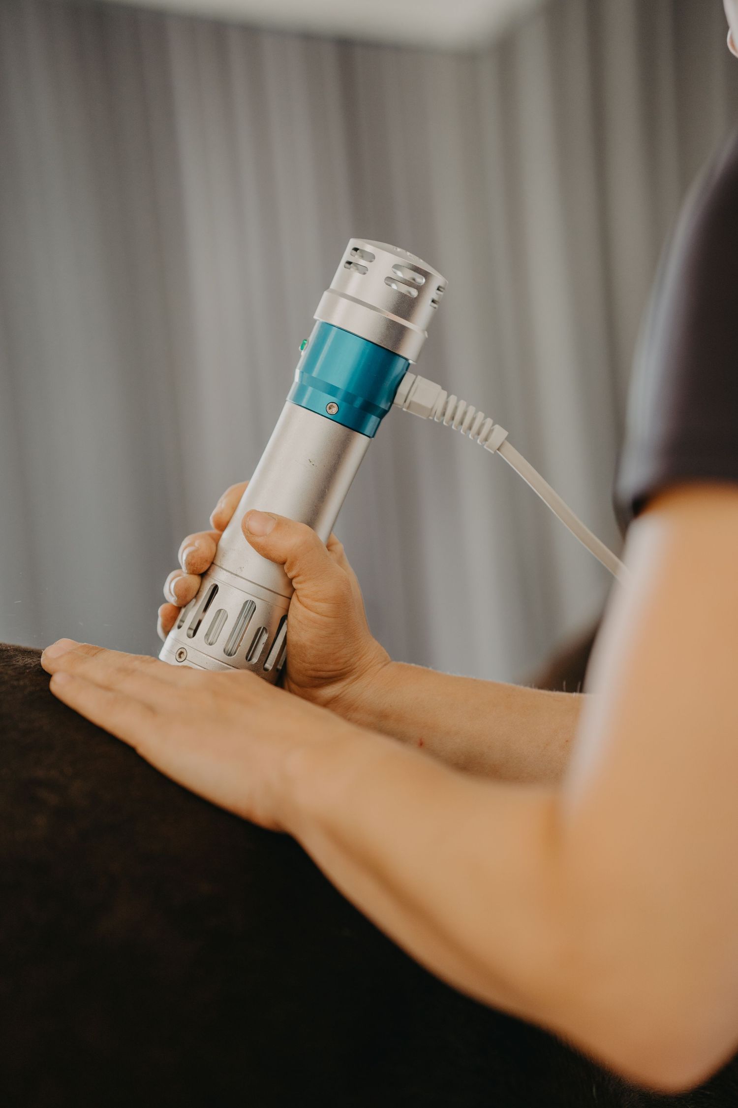 A hand holds a small white and turquoise medicine inhaler against a blurred background.