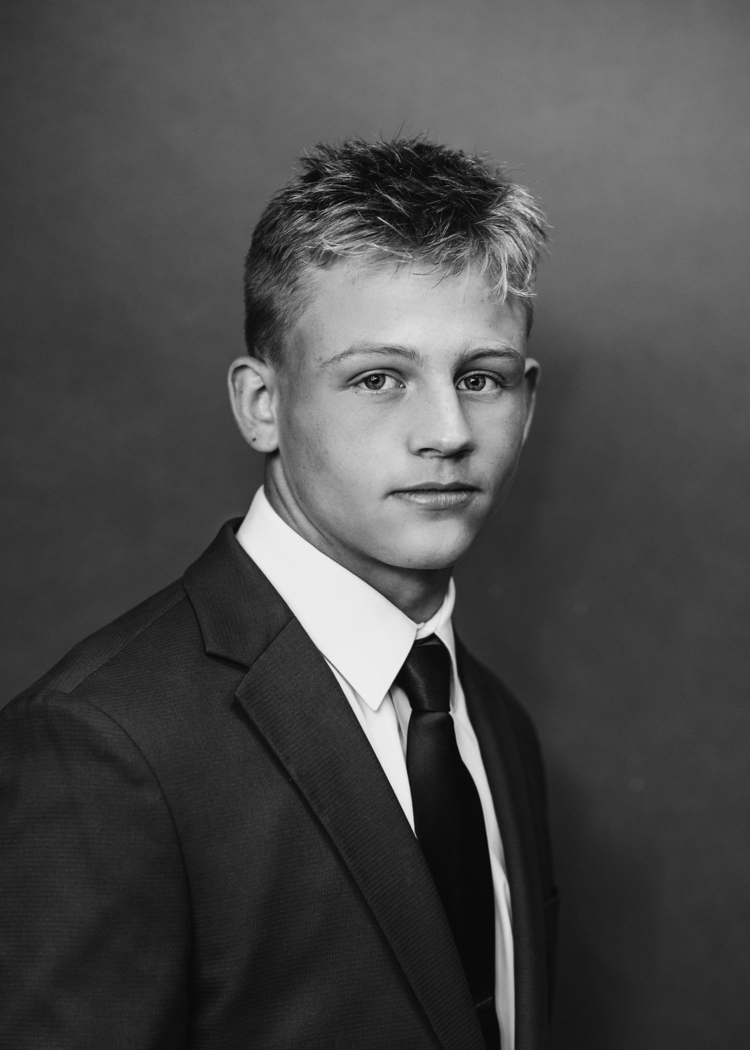 Black and white formal portrait of student in dark suit and tie.