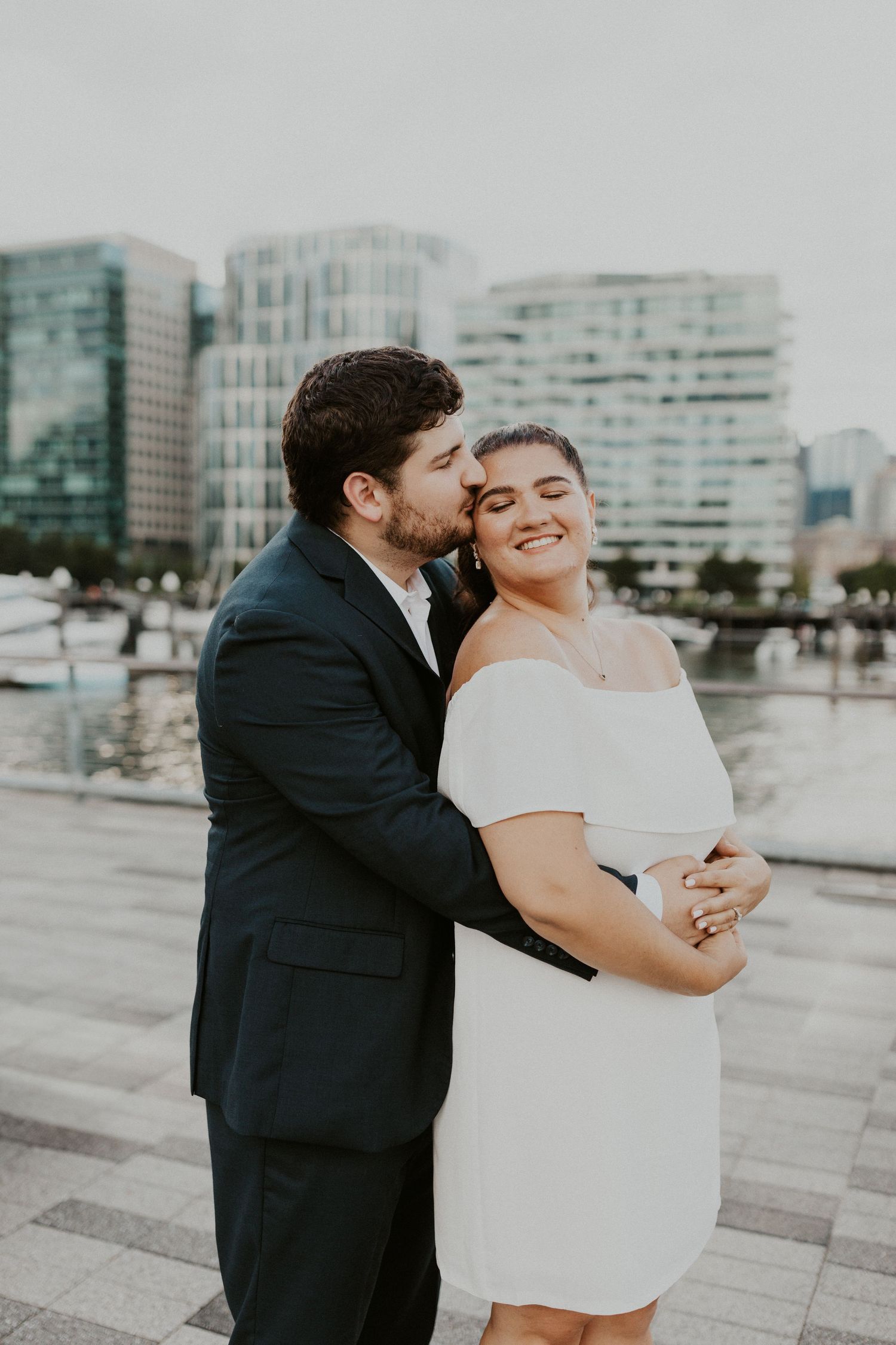 Couple sharing romantic moment in front of urban cityscape with modern buildings in background.