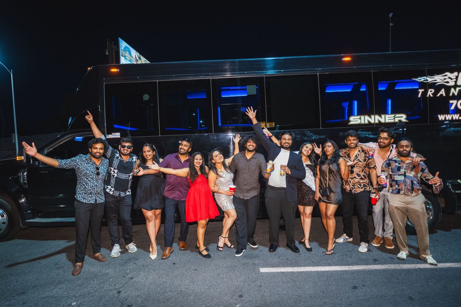 Group of friends posing outside a party bus at night in Las Vegas.