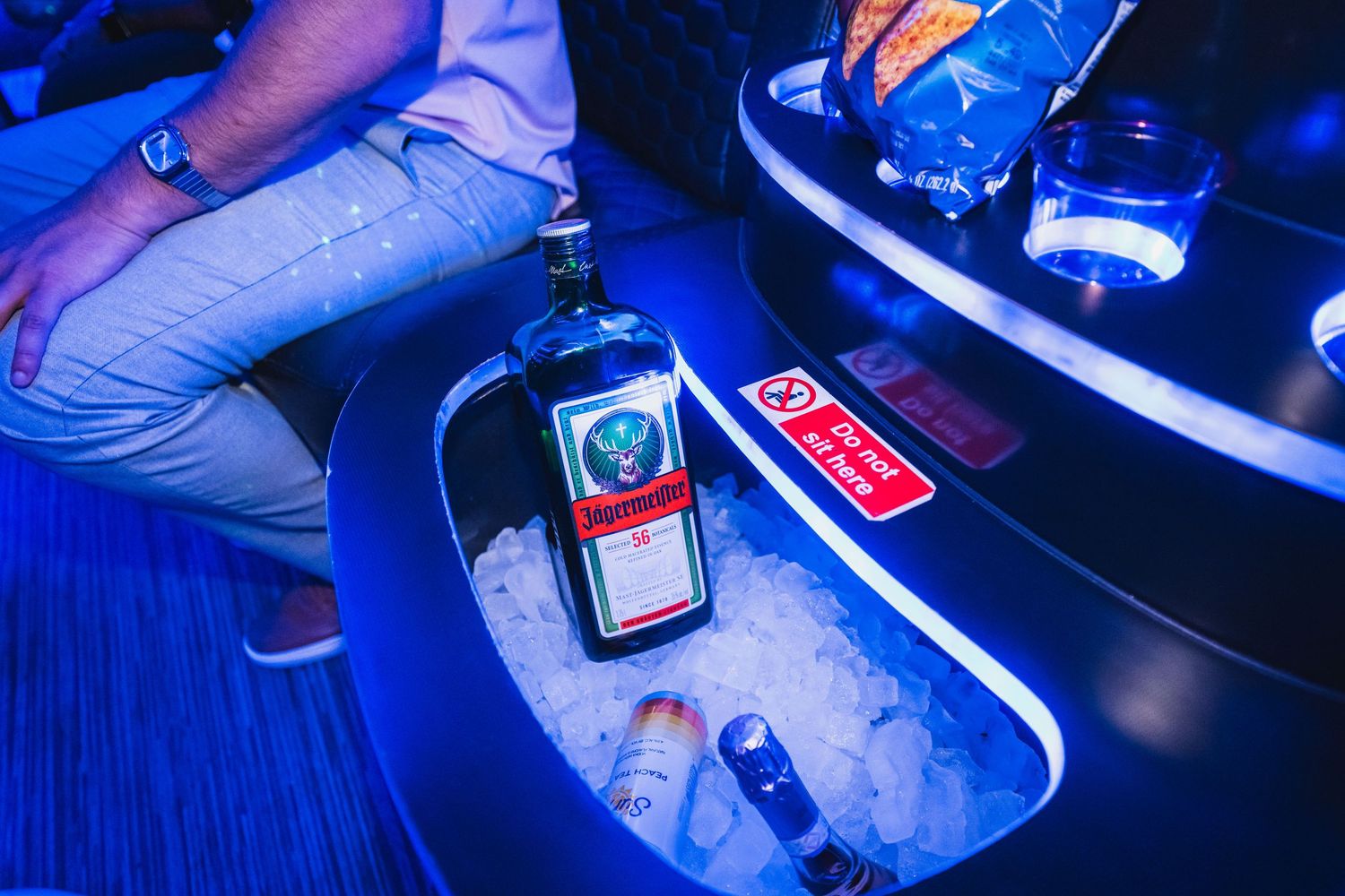 Jagermeister bottle chilling on ice in a glowing blue party bus drink holder.