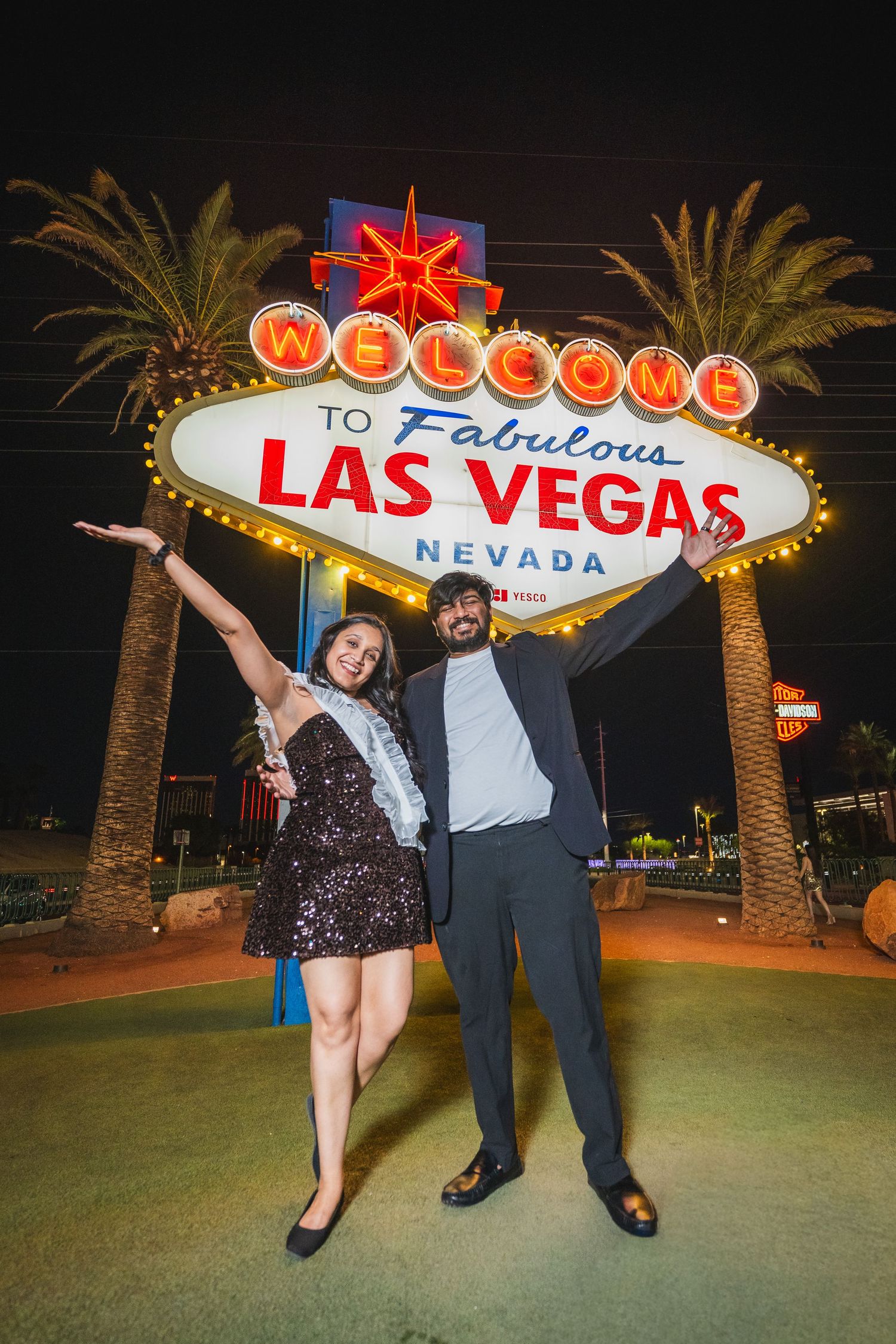 Couple celebrating in front of the iconic Welcome to Fabulous Las Vegas Nevada sign at night.