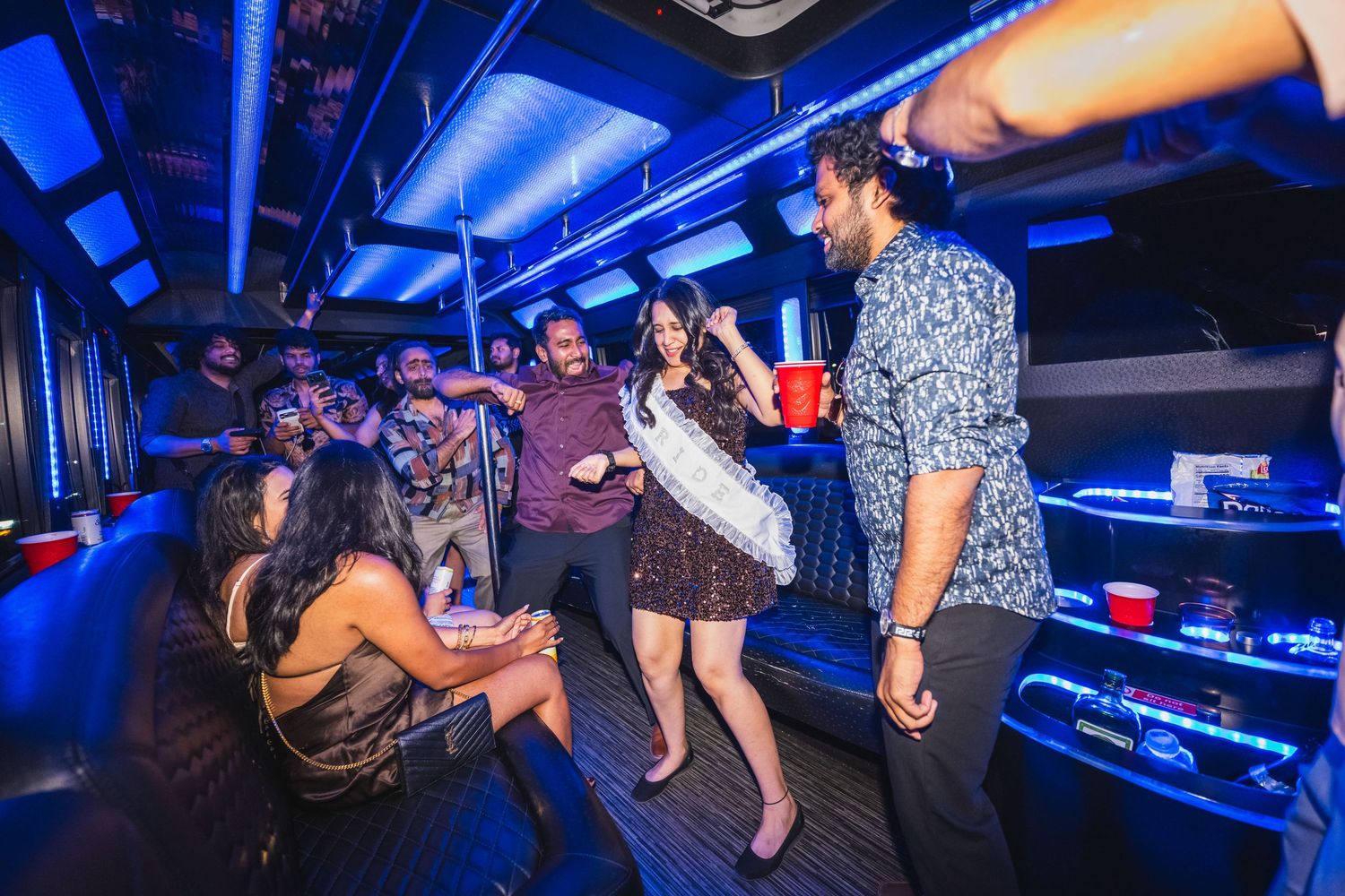 Group of friends dancing and having fun inside a neon-lit party bus in Las Vegas.