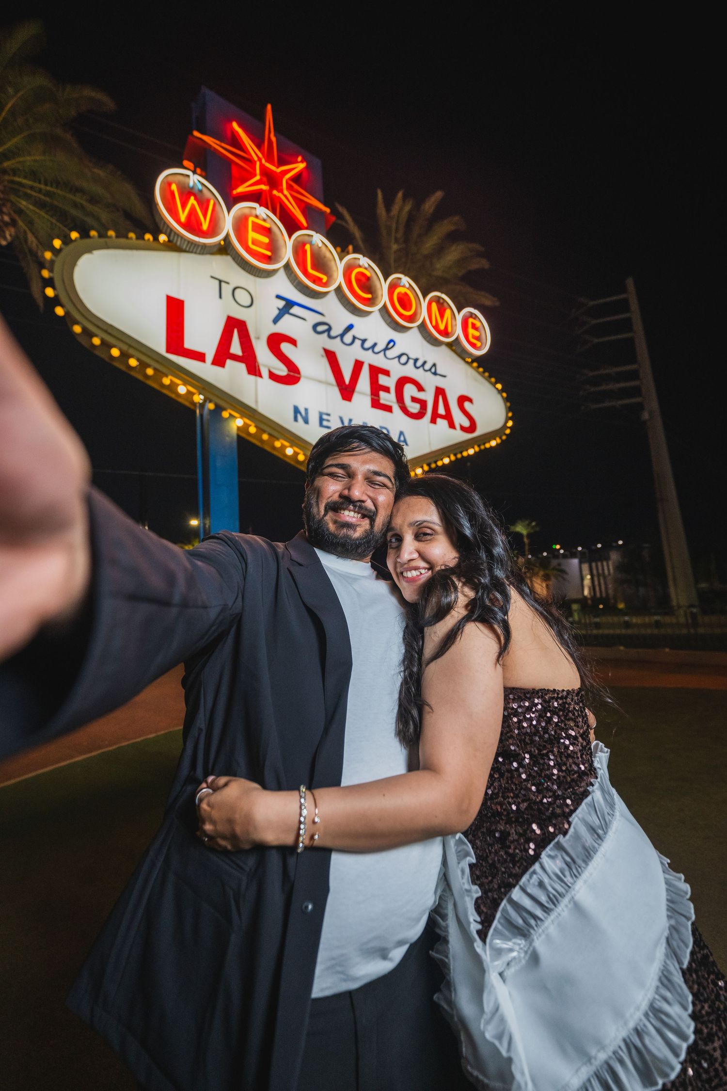 Couple taking a selfie at the iconic Welcome to Fabulous Las Vegas Nevada sign at night.