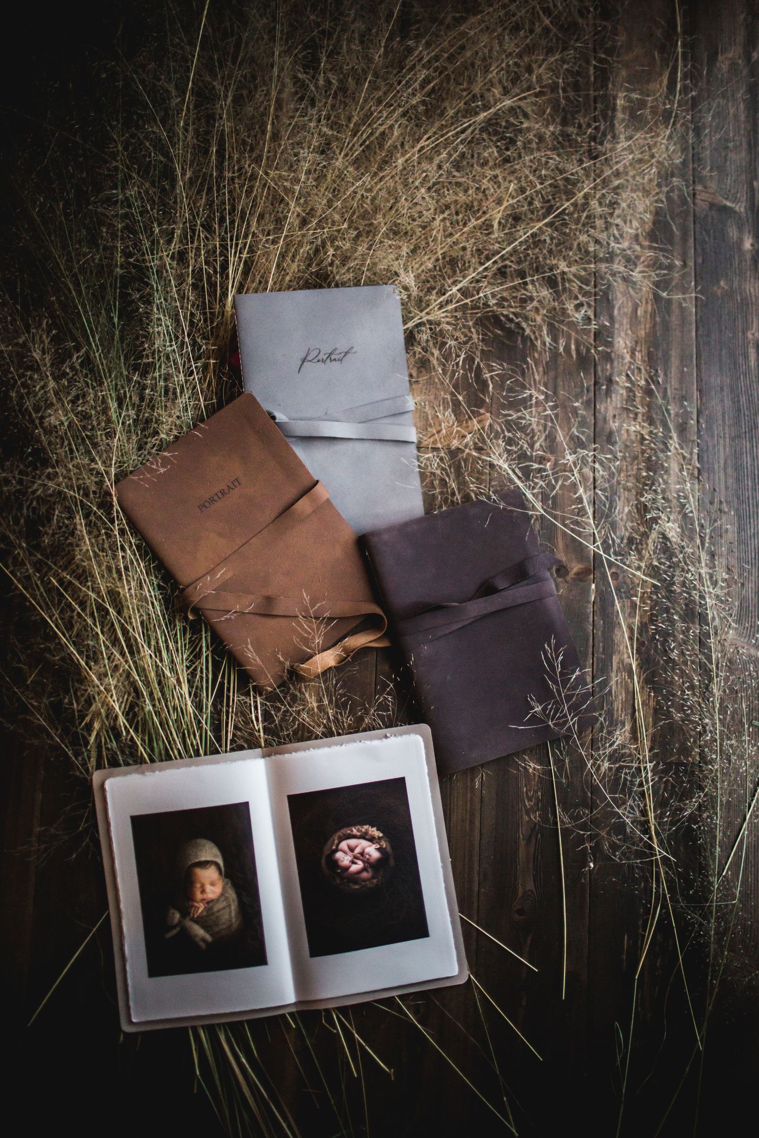 Artistic flat lay of vintage photo prints and leather portfolios against textured dark background.