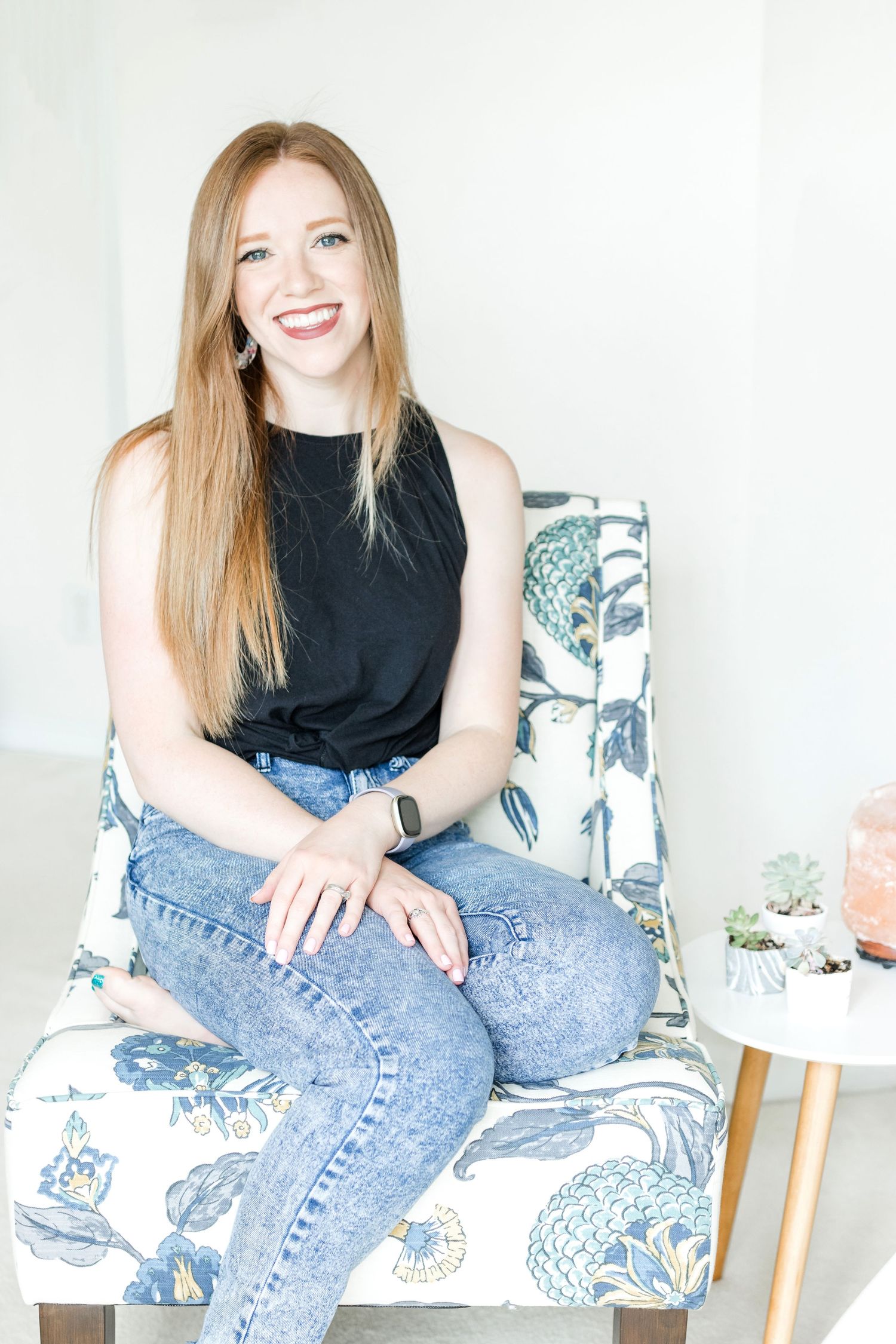 A casual lifestyle photoshoot on a white couch with blue jeans and black top.