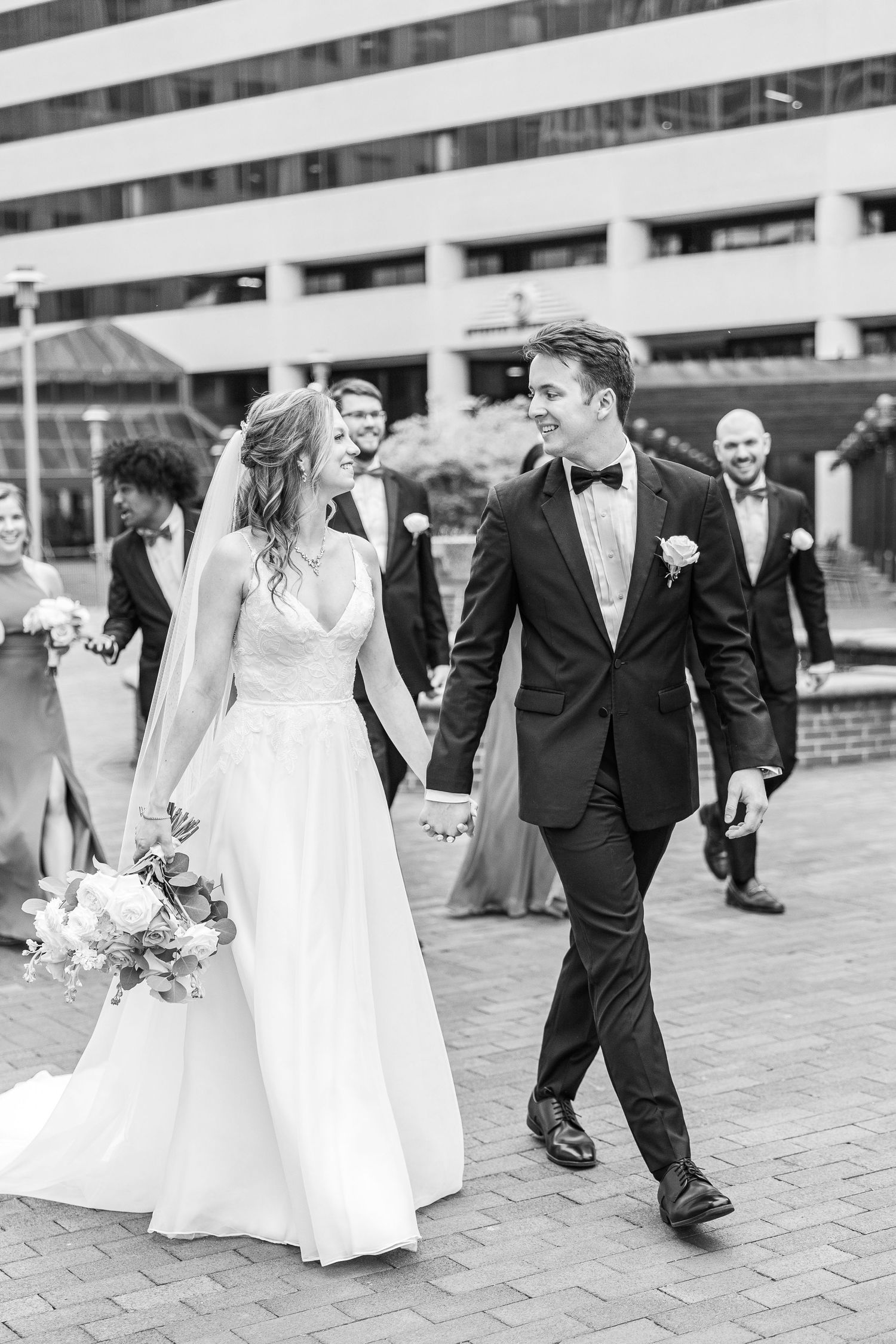 Black and white sequence showing wedding party walking and interacting on brick pavement.