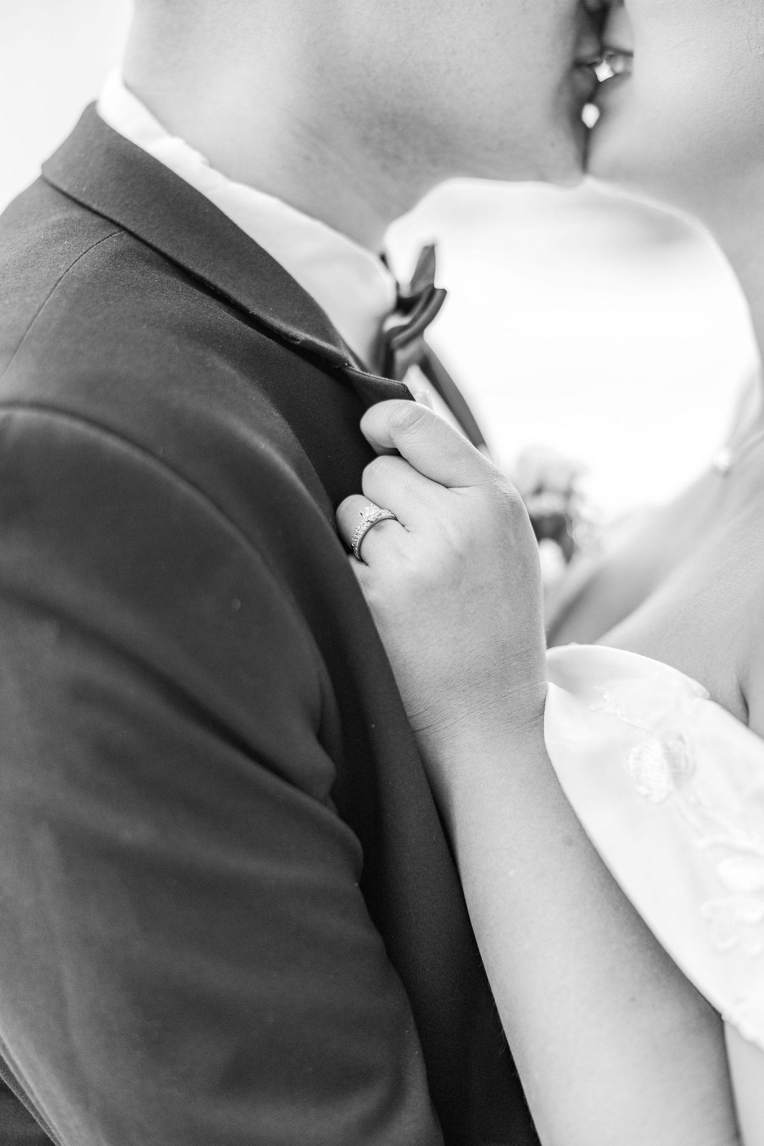 Black and white close-up details of formal wedding attire and rings.
