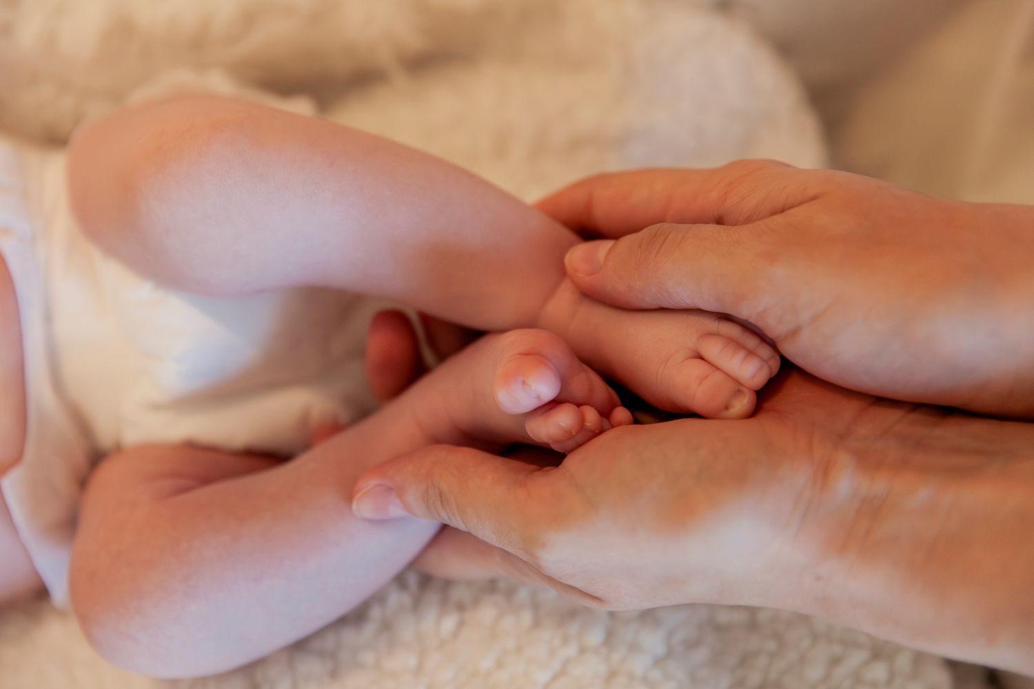 Close-up shots of hands gently touching against a soft beige background.