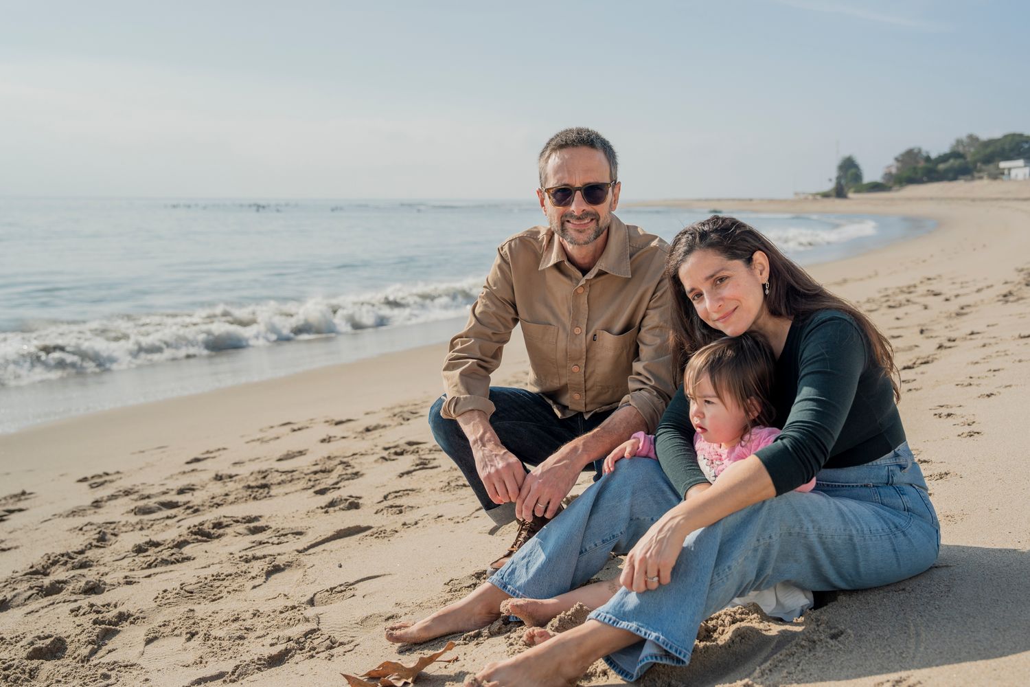 Family enjoying quality time together while playing in the sand at a sunny beach during golden hour.