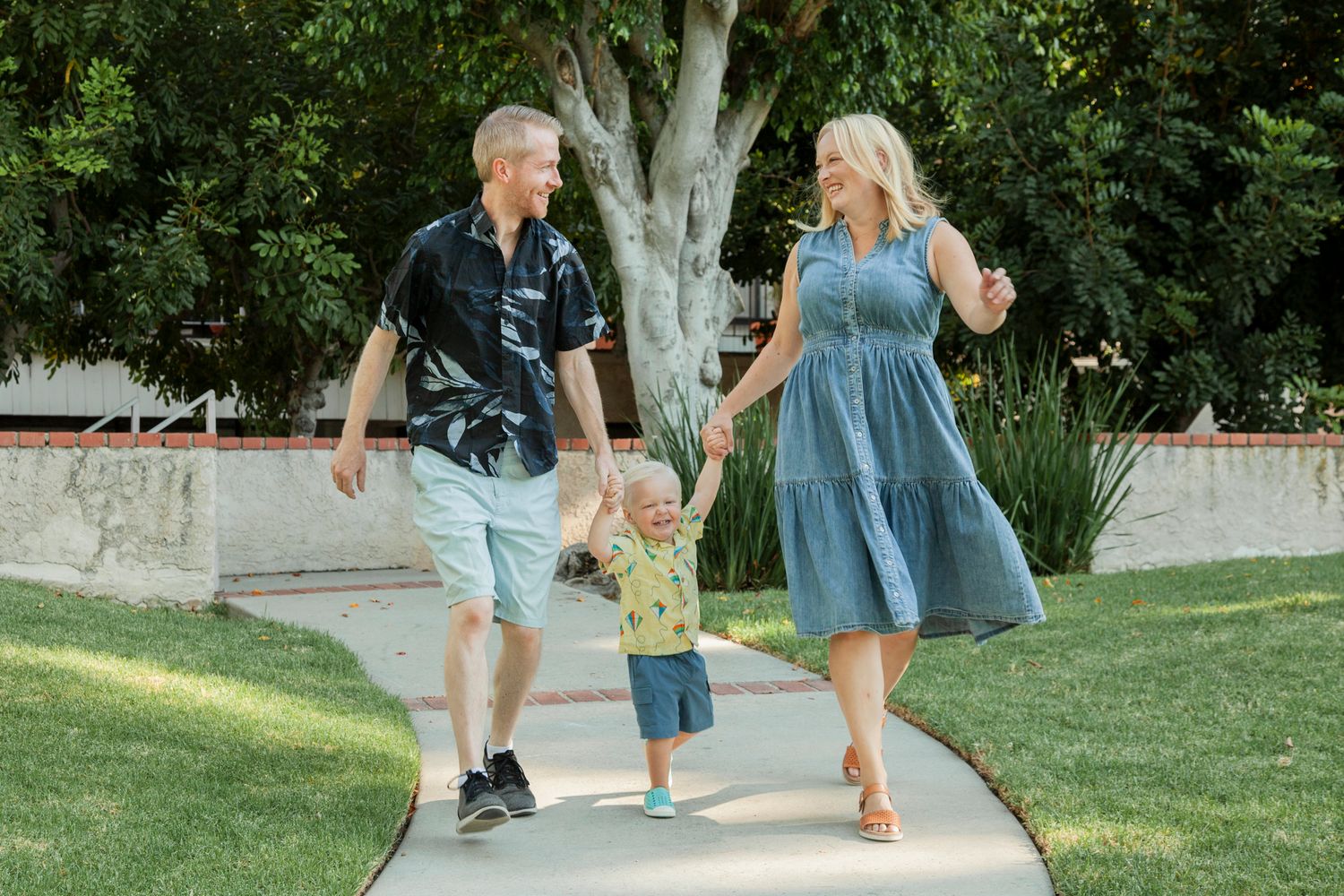 People walking together on a garden path surrounded by lush greenery and trees.