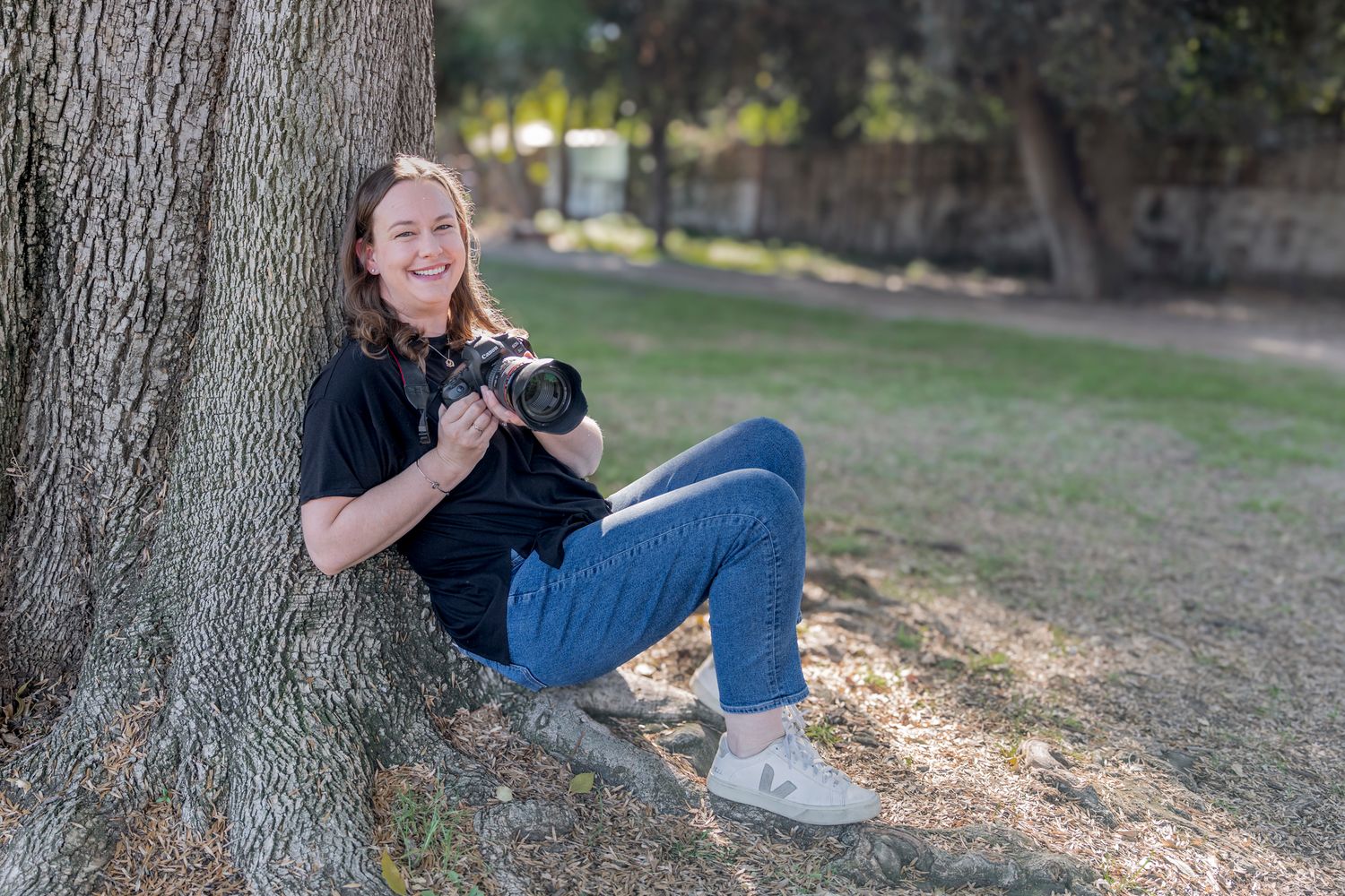 Natural light portrait session with tree trunk backdrop in outdoor setting.