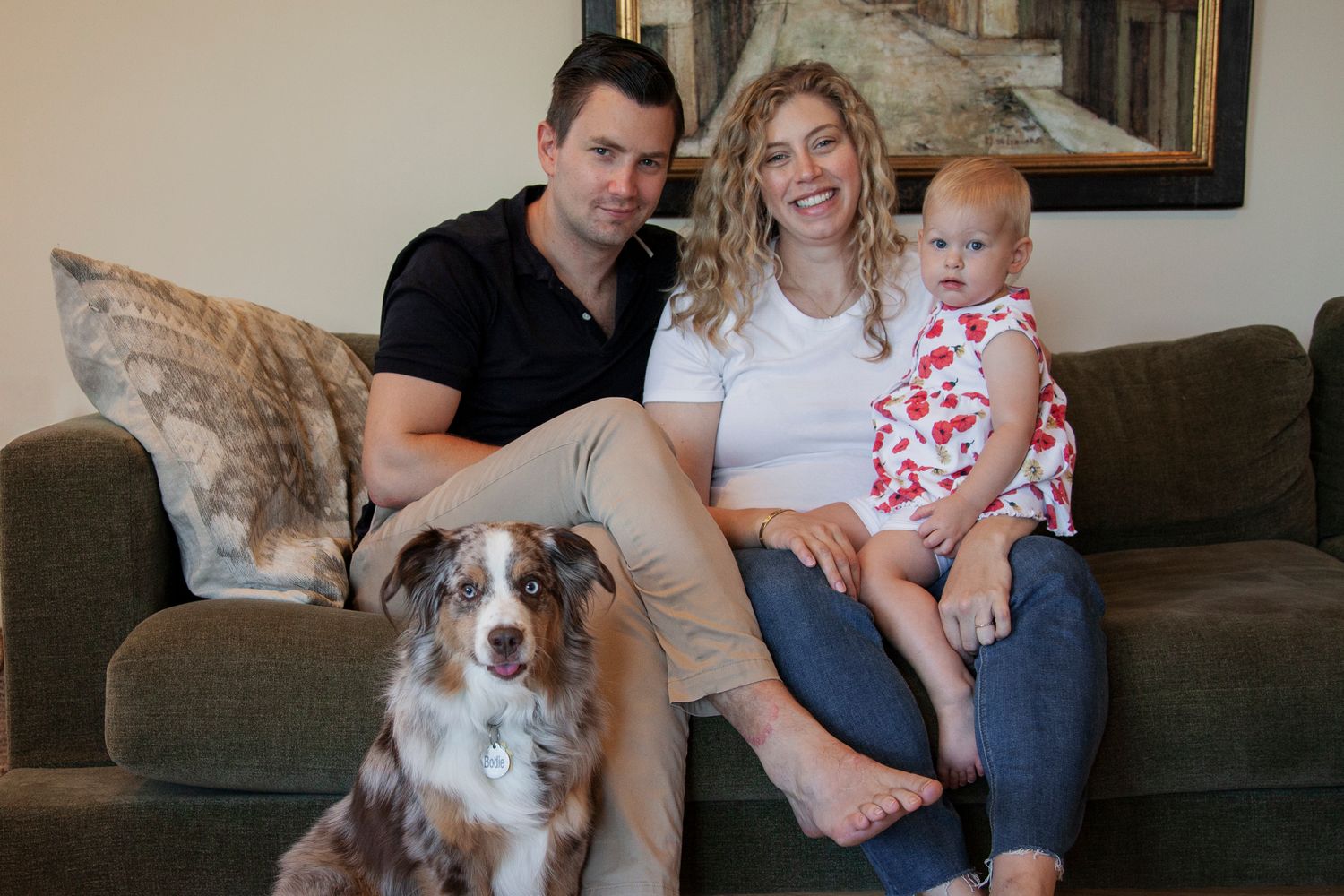 A family sits on a brown couch with their Australian Shepherd dog in a series of casual indoor photos.
