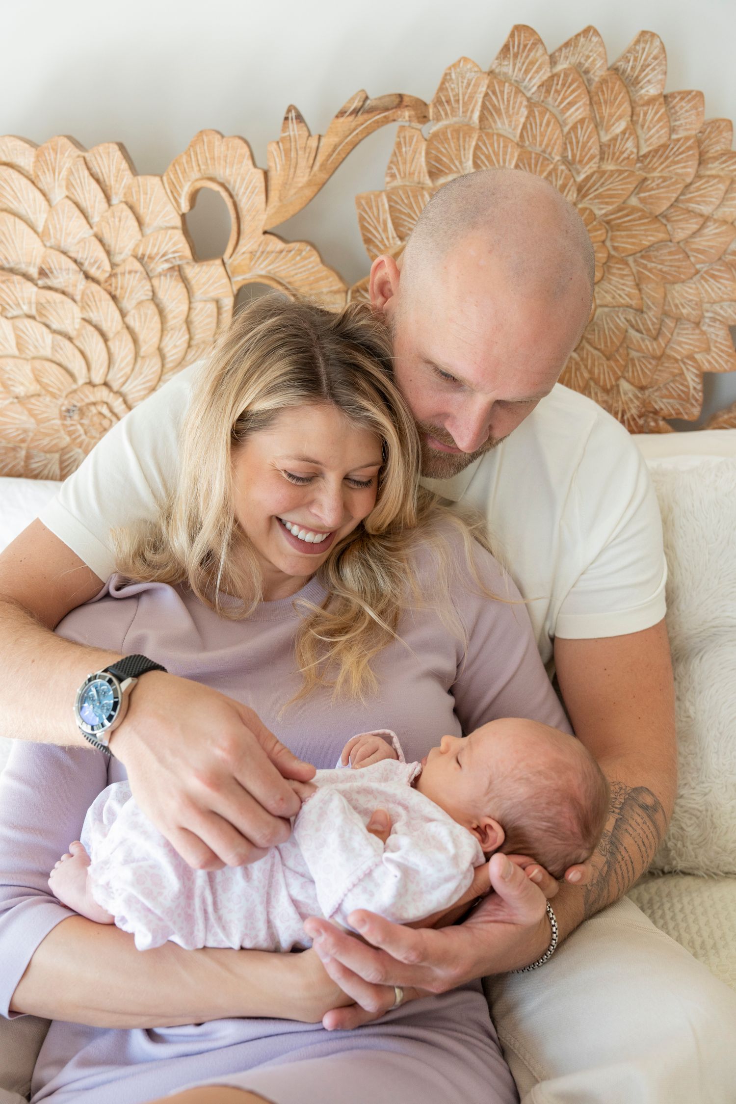 A couple lies on a couch snuggling with their newborn baby in a series of tender family moments.