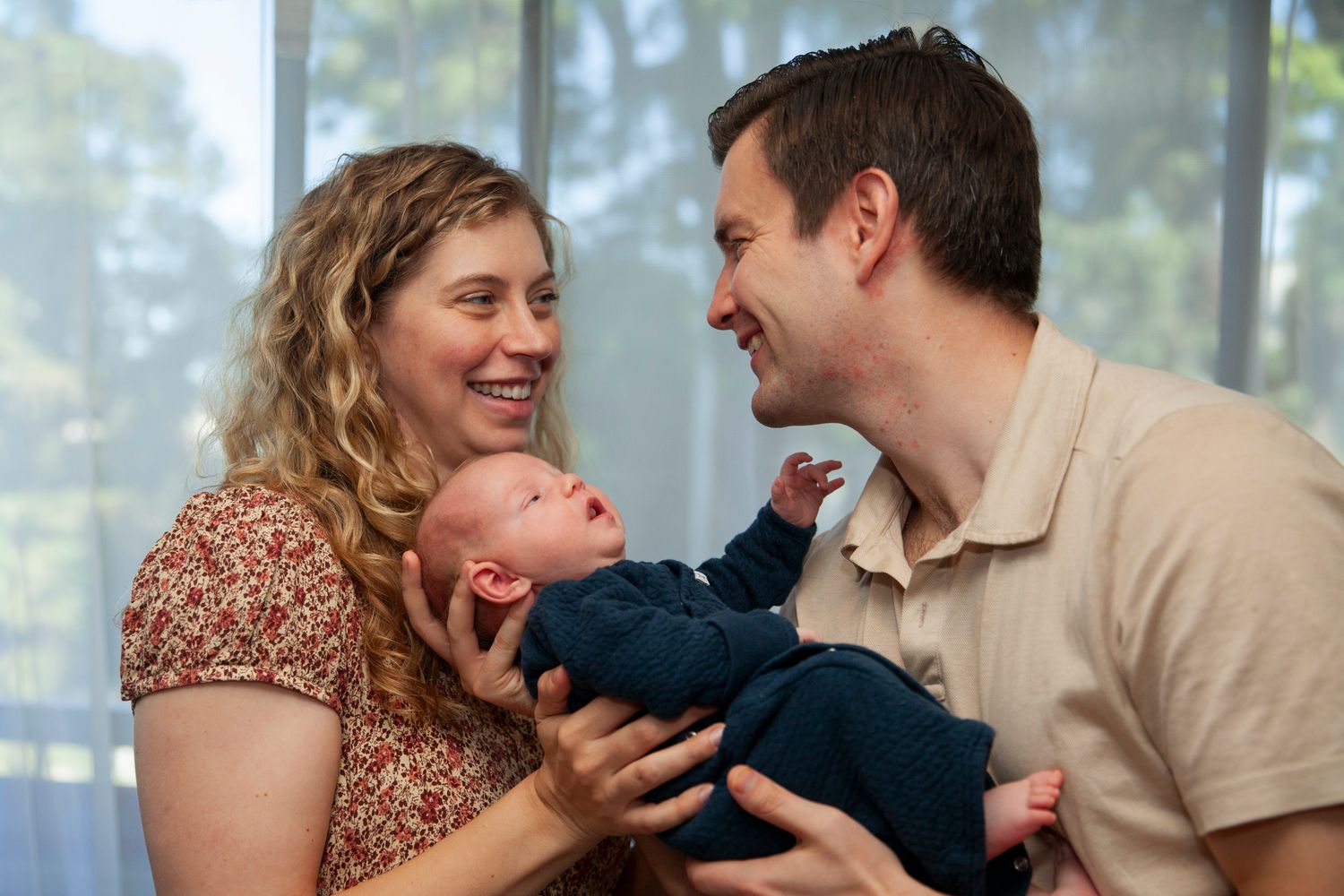 A family shares a joyful moment together outdoors with natural lighting and blurred trees in the background.