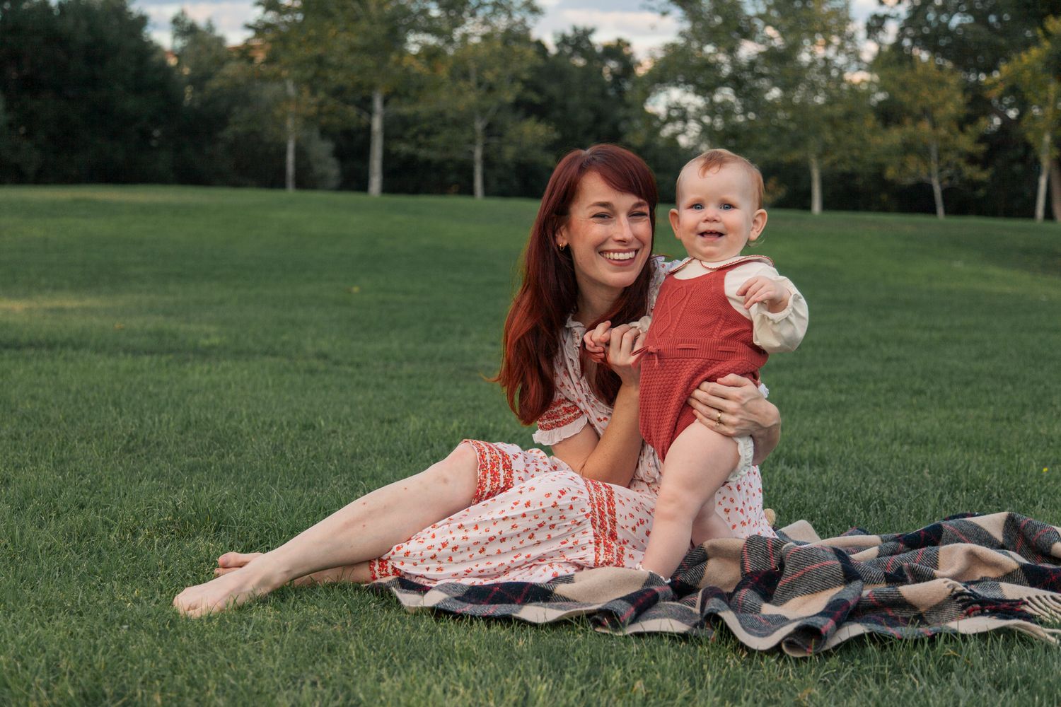 A joyful moment shared between people relaxing on a blanket in a lush green park setting.