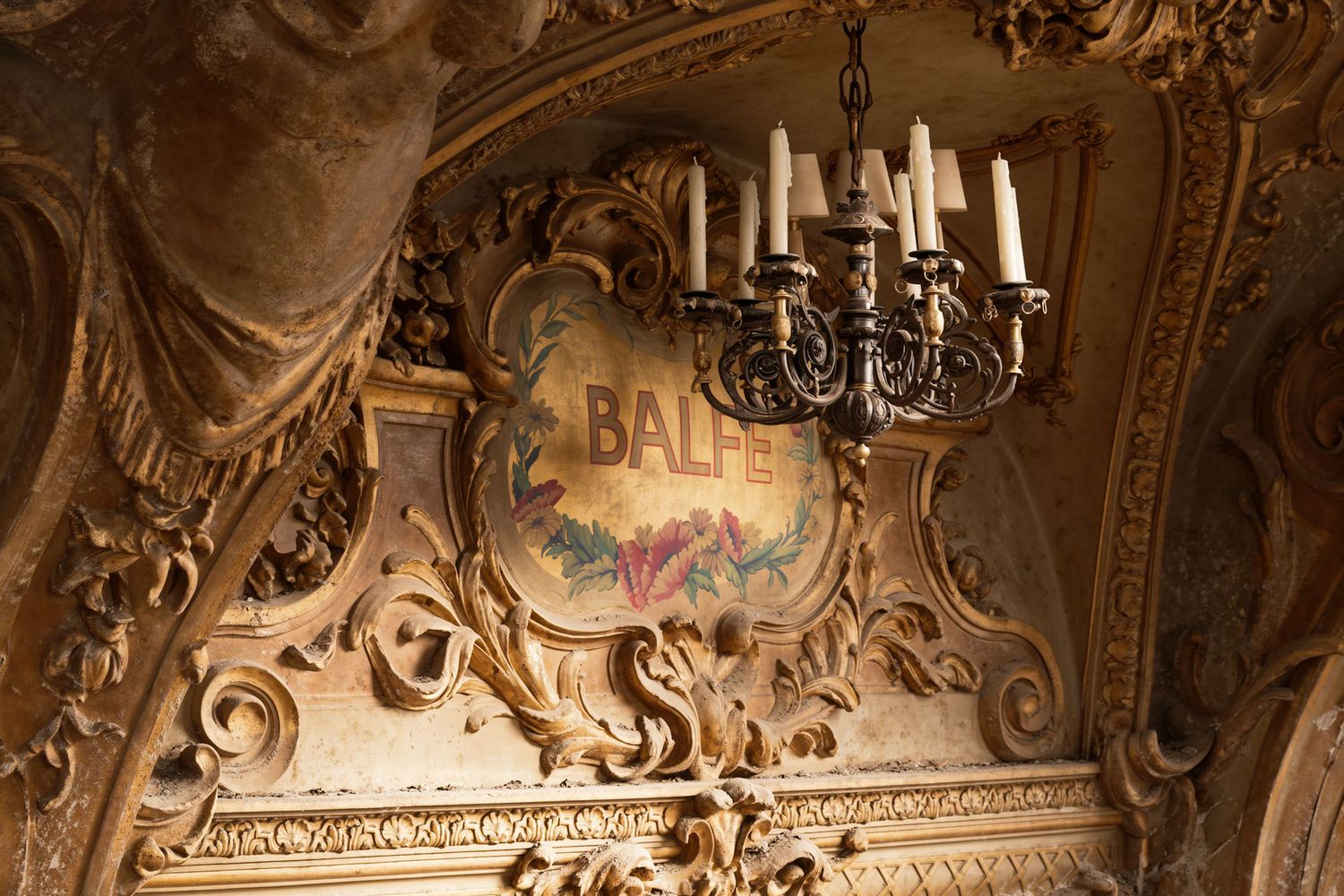 Ornate gilded theater balcony with candelabra chandelier and decorative BALPE sign in a grand opera house.