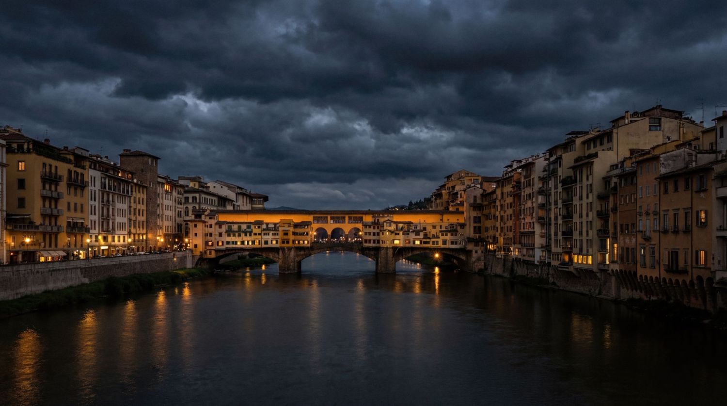 Ponte Vecchio bridge illuminated at dusk over the Arno River in Florence, Italy, under dramatic stormy skies.